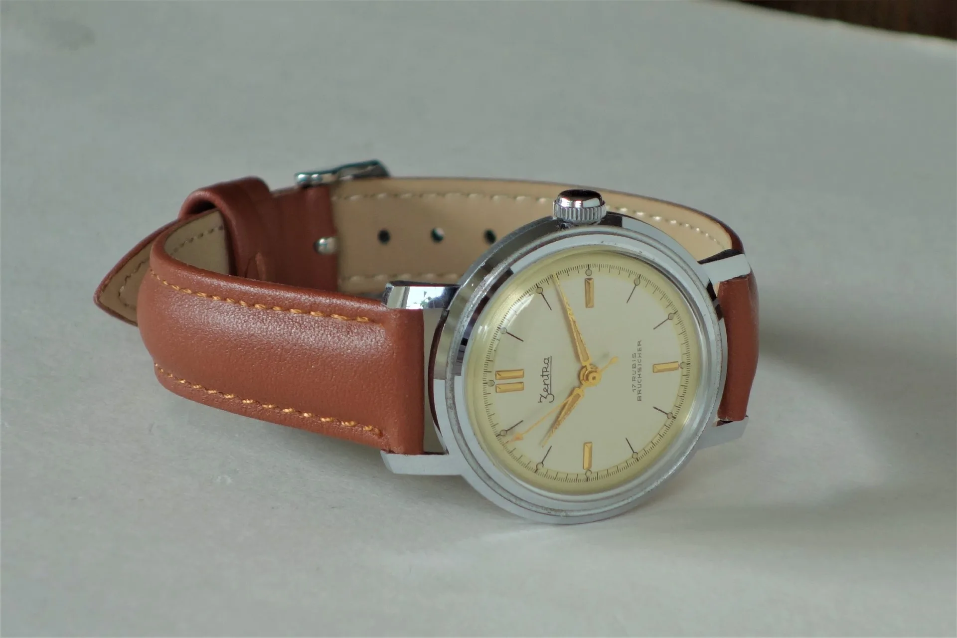 Analoge Armbanduhr mit beigem Zifferblatt und braunem Lederarmband.