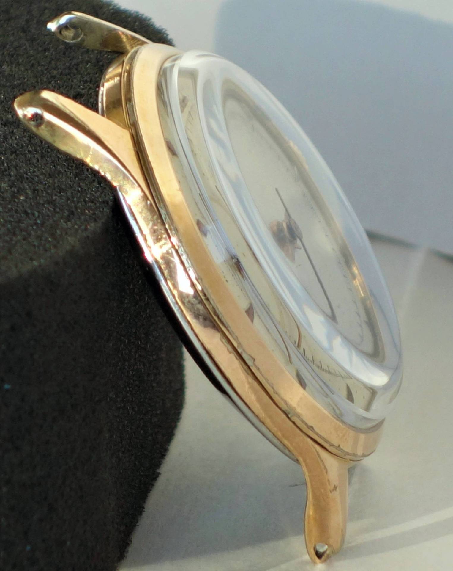 Goldfarbenes Uhrgehäuse mit transparenter Abdeckung und sichtbaren Bandanstößen.