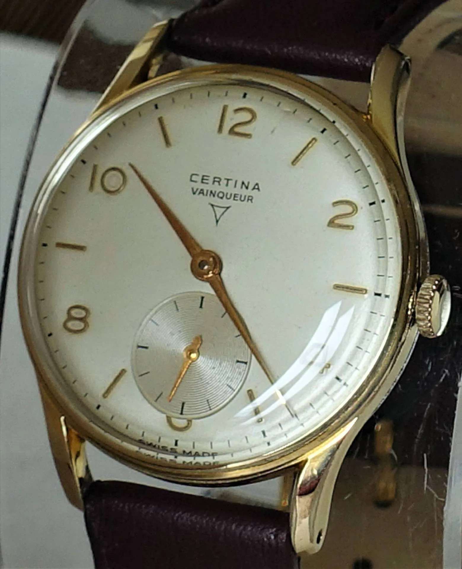 Certina Vainqueur Uhr Analoge Armbanduhr mit hellem Zifferblatt, goldfarbenem Gehäuse und braunem Armband.