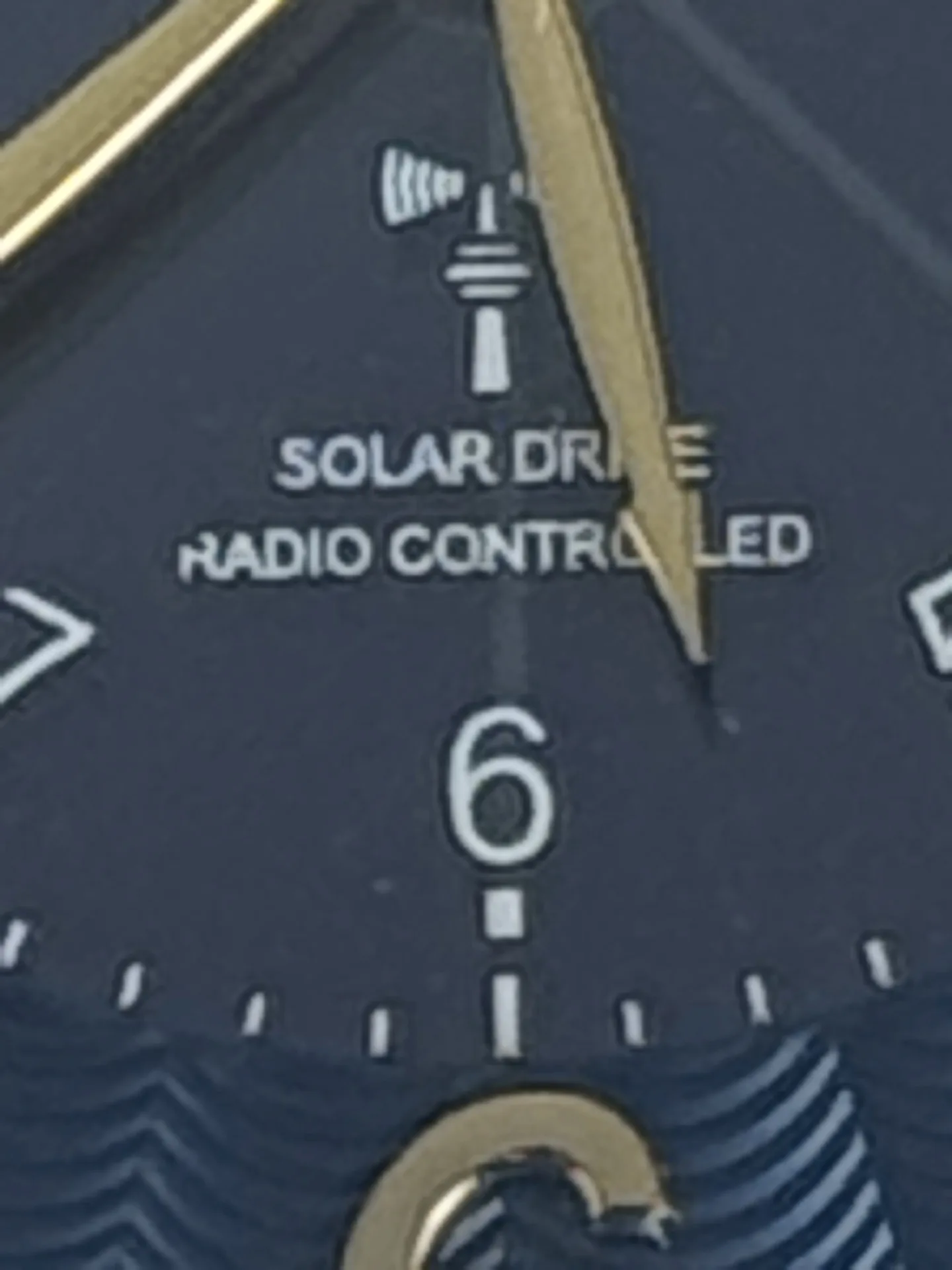 Nahaufnahme eines blauen Zifferblatts mit goldfarbenem Zeiger, Funk- und Solar-Drive-Aufschrift.