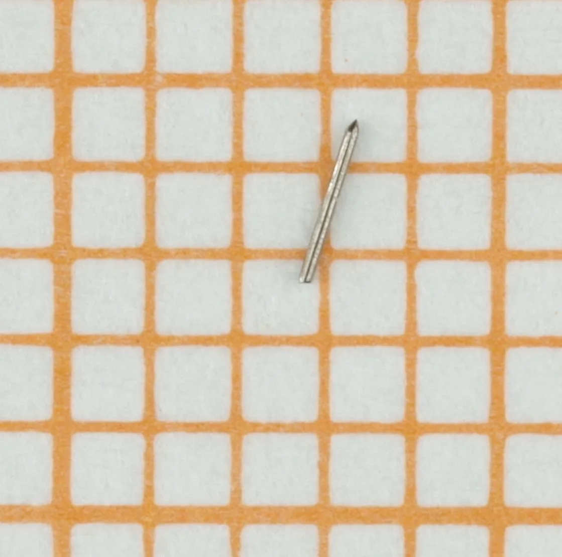Kleiner, silberfarbener Wellenstift aus Stahl auf Millimeterpapier.