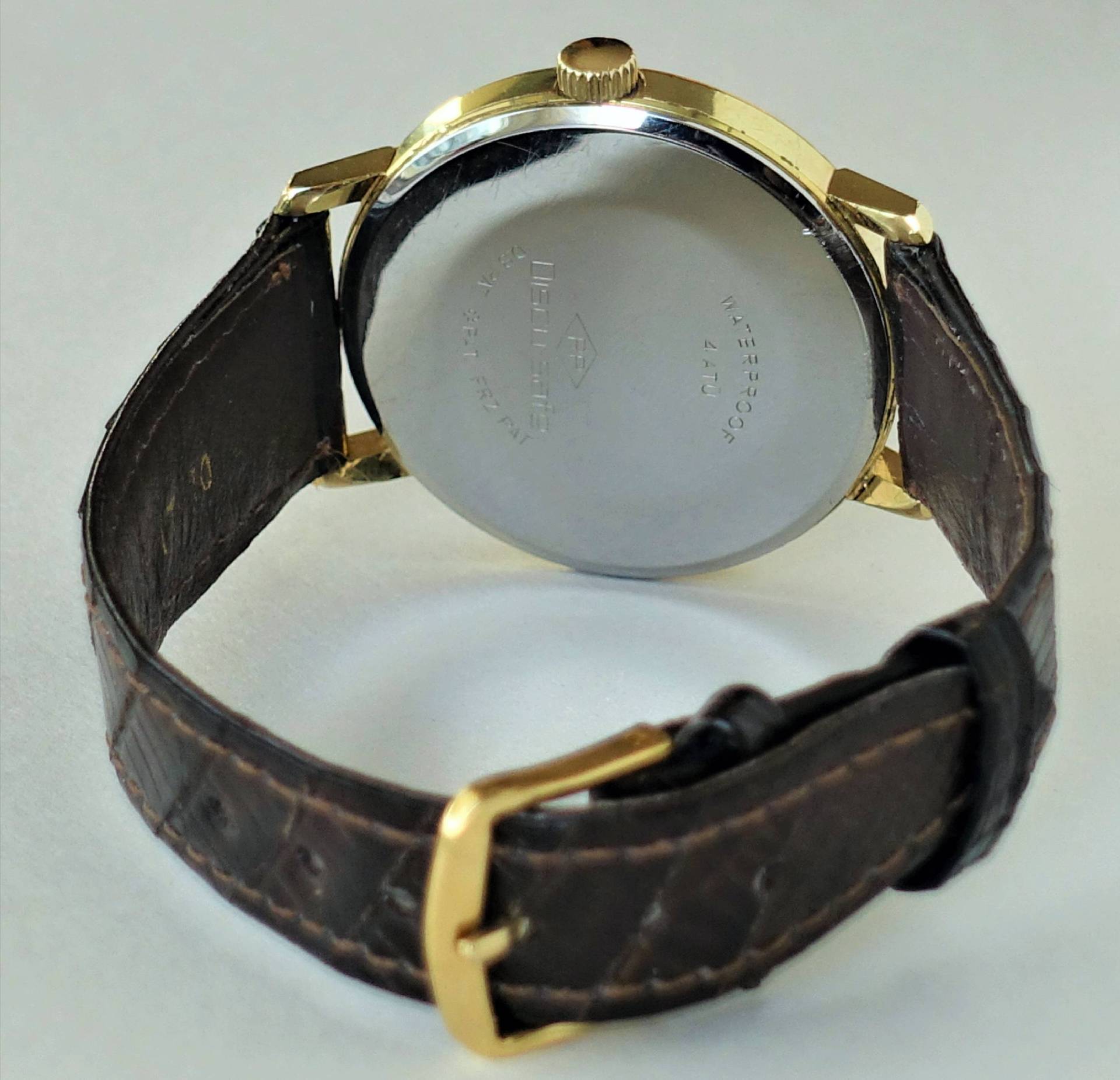 Armbanduhr mit braunem Armband, goldfarbenem Gehäuse und silberfarbener Rückseite, Marke Poljot.