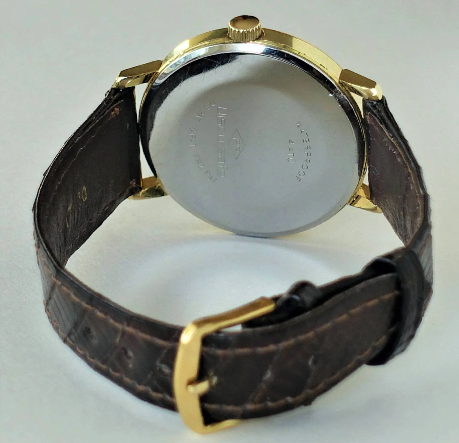 Poljot Armbanduhr braun Armbanduhr mit braunem Armband, goldfarbenem Gehäuse und silberfarbener Rückseite, Marke Poljot.