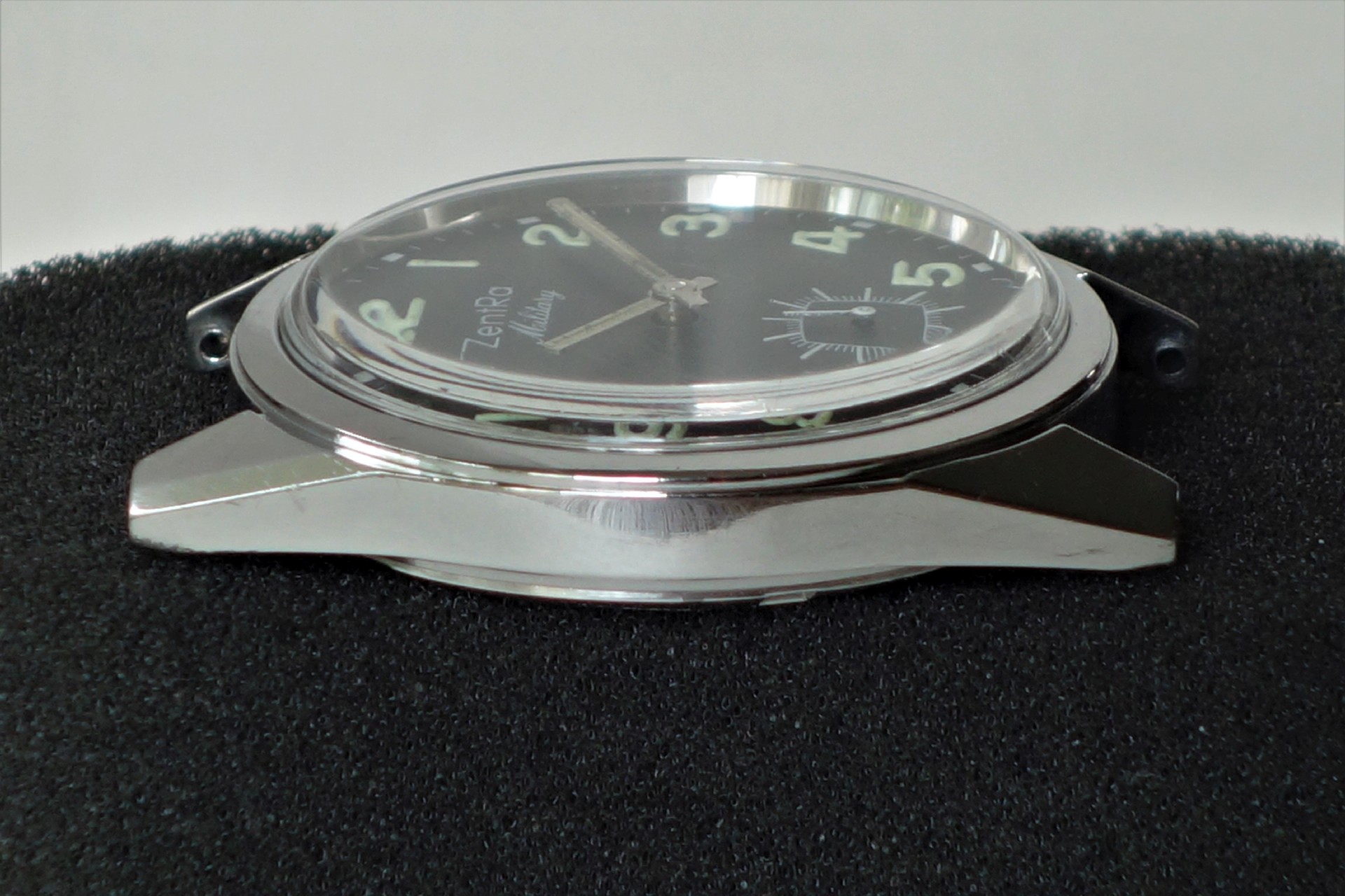 Silberfarbene Armbanduhr mit schwarzem Zifferblatt und Leuchtzahlen.