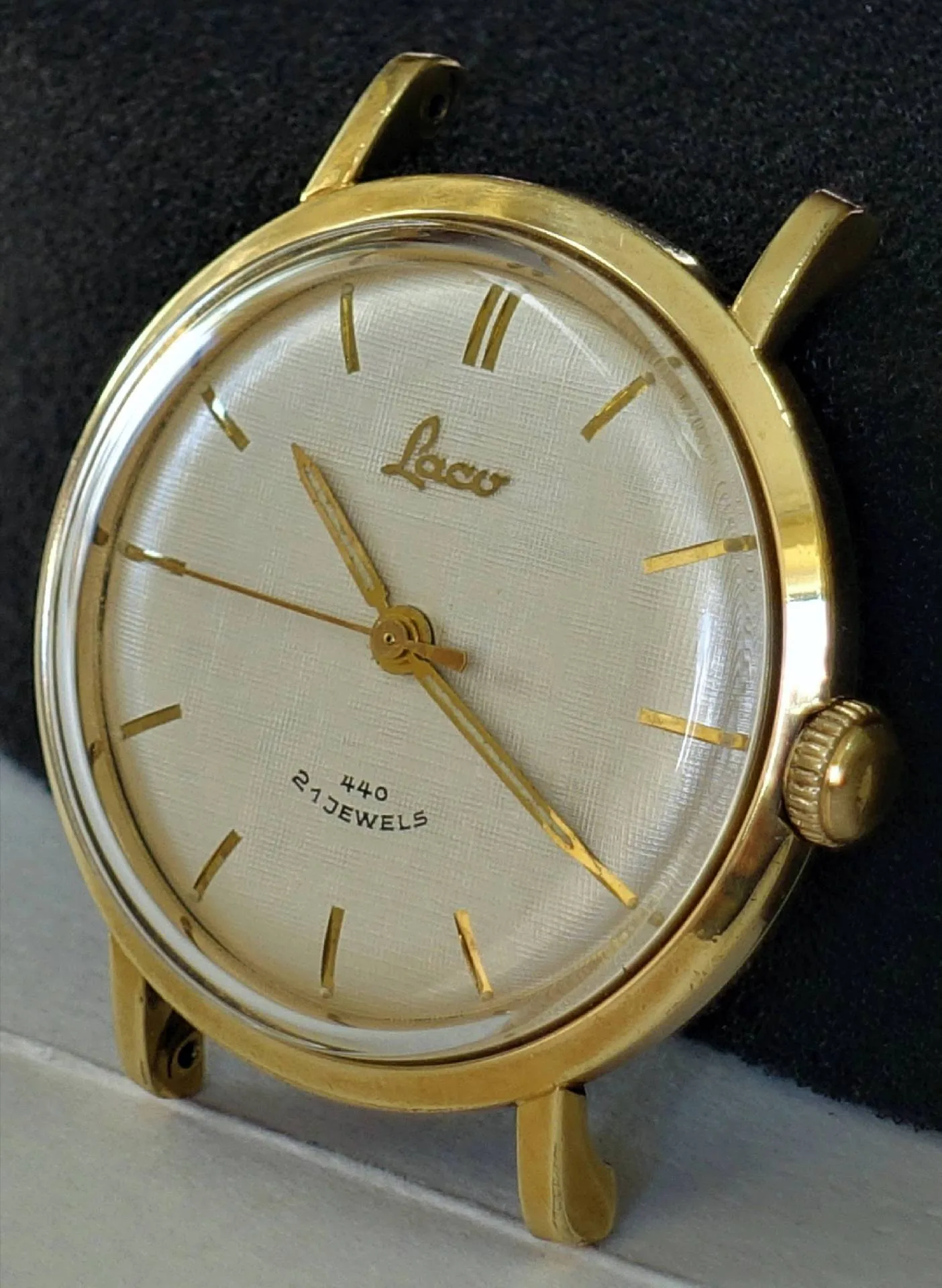 Runde Armbanduhr mit goldfarbenem Gehäuse und Zeigern, hellem Zifferblatt und minimalistischen Indizes.