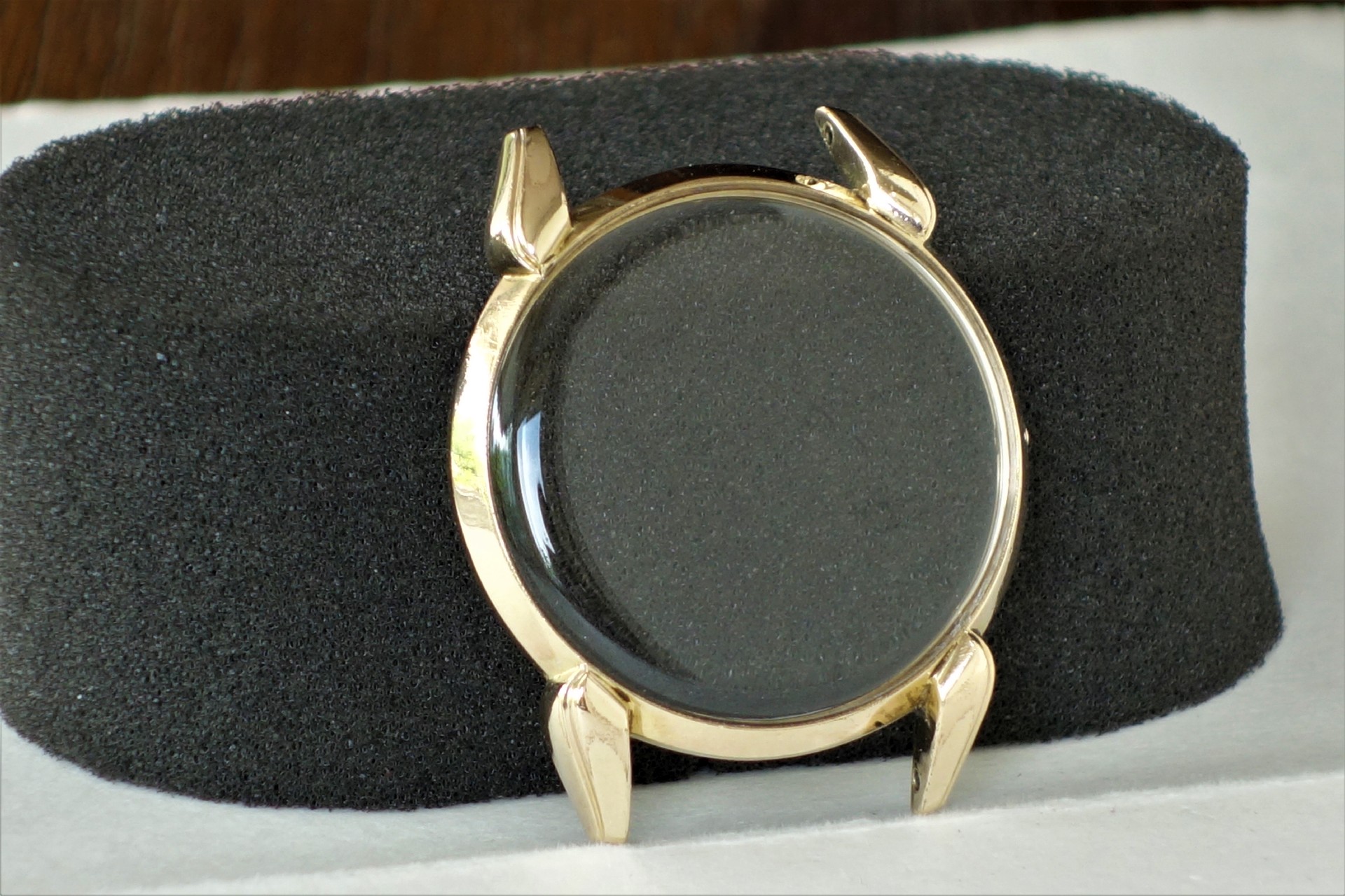 Rundes Uhrengehäuse in goldfarbener Optik mit montiertem Uhrglas.