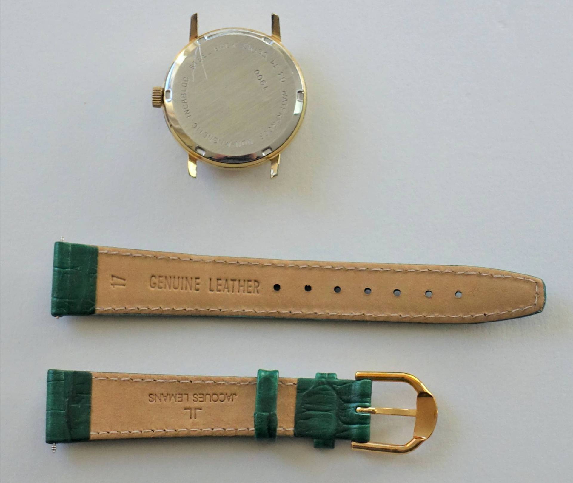 Goldfarbenes Uhrgehäuse mit grünem Lederarmband und goldfarbener Dornschließe.