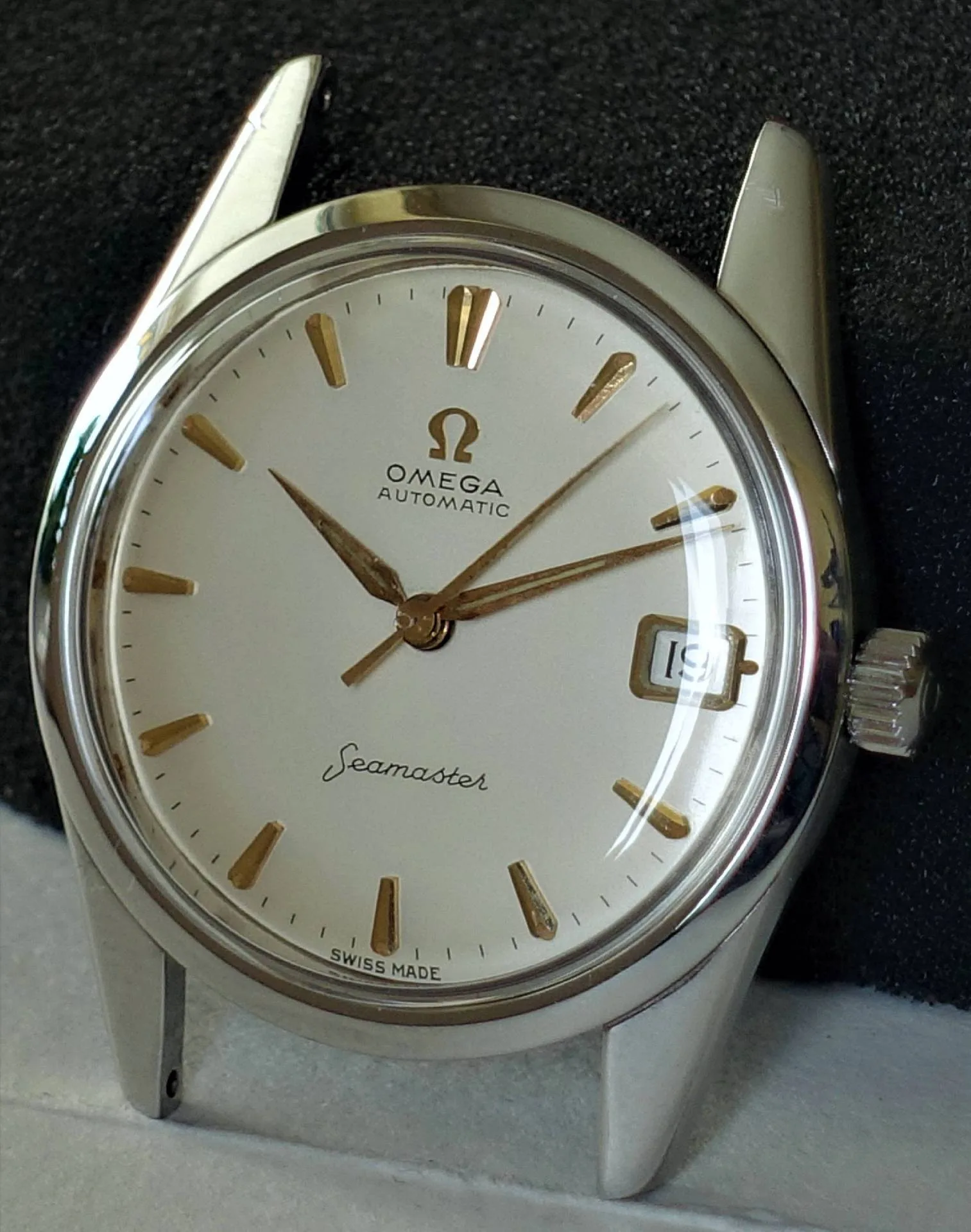 Omega Seamaster Armbanduhr Silberne Armbanduhr mit weißem Zifferblatt und goldfarbenen Zeigern und Indizes.