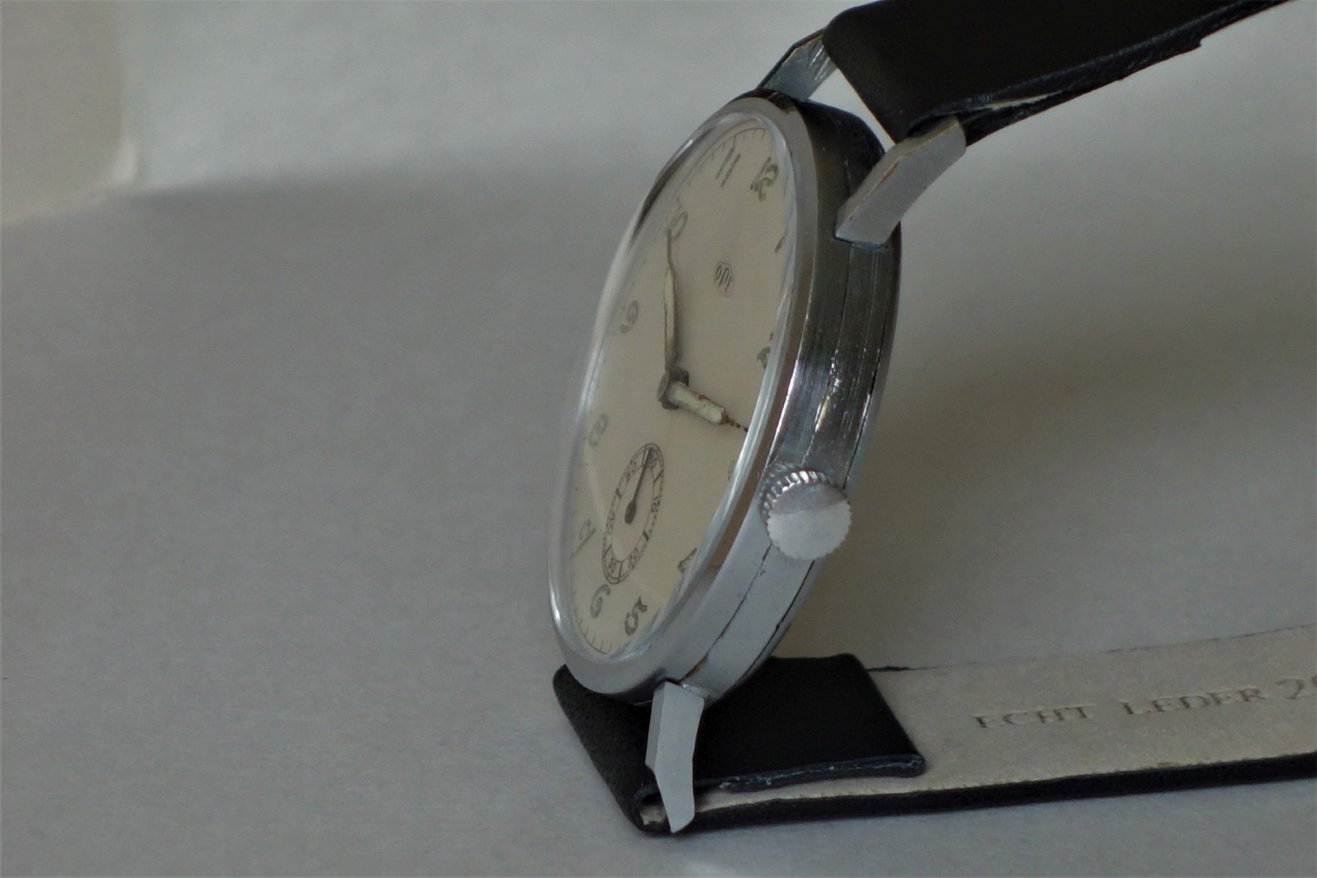 Analoge Armbanduhr mit silberfarbenem Gehäuse, weißem Zifferblatt und schwarzem Armband.