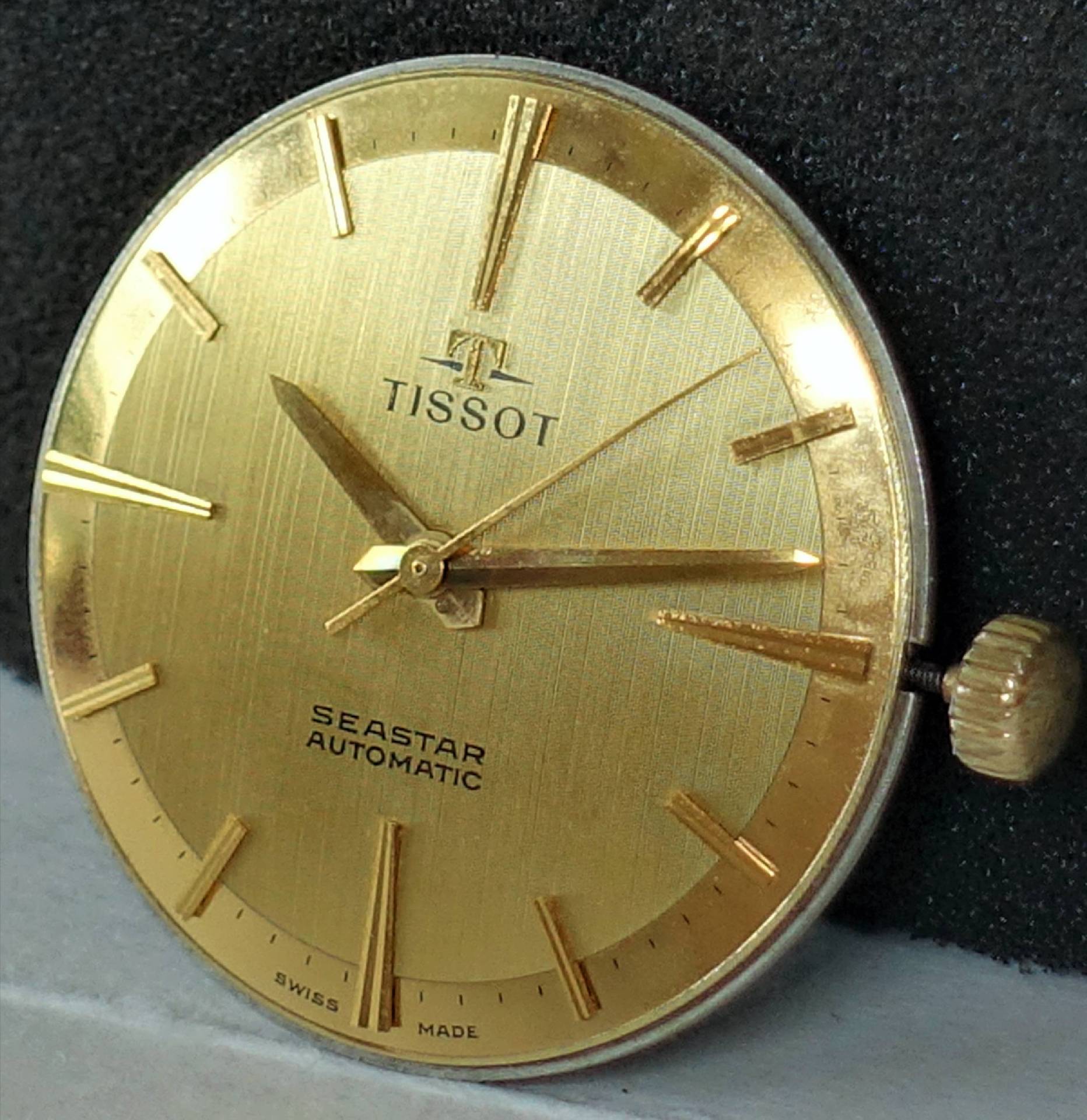 Goldenes Uhrwerk mit Zifferblatt und Zeigern, Aufschrift Tissot Seastar Automatic.