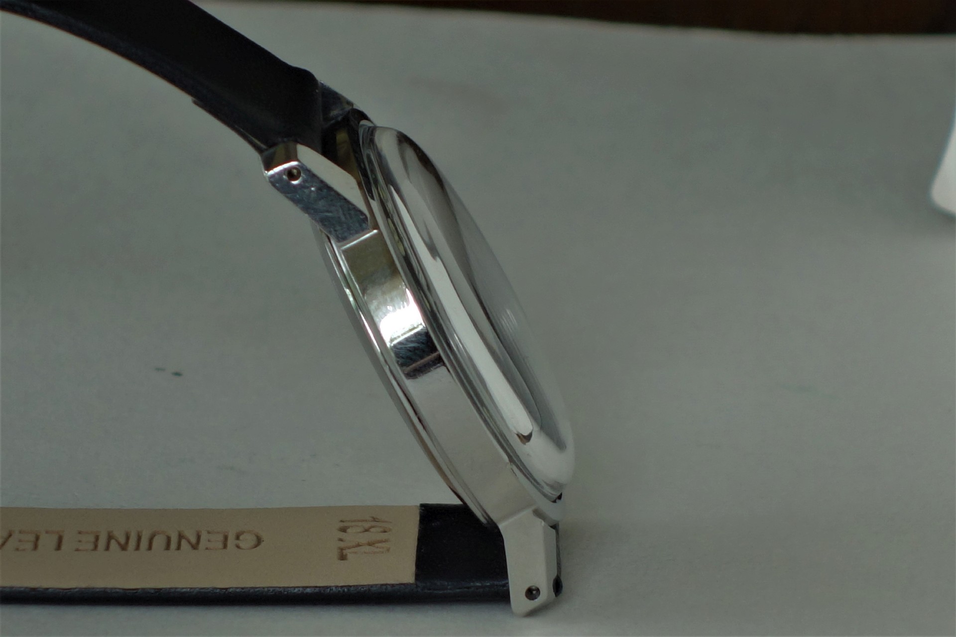 Silberfarbene Armbanduhr mit schwarzem Lederarmband in Seitenansicht.