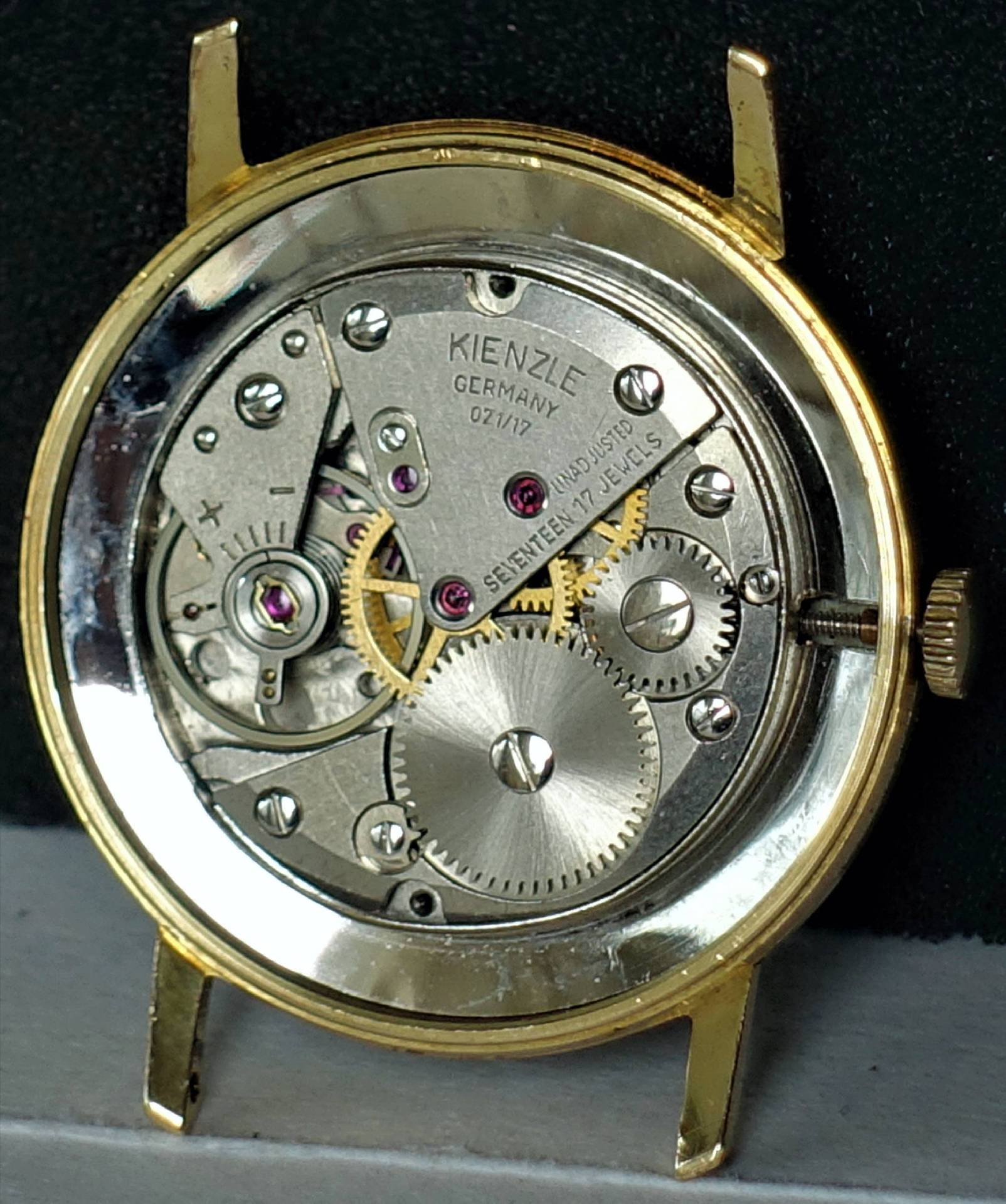 Mechanisches Uhrwerk von Kienzle in einem goldfarbenen Gehäuse, sichtbare Zahnräder und Schrauben.