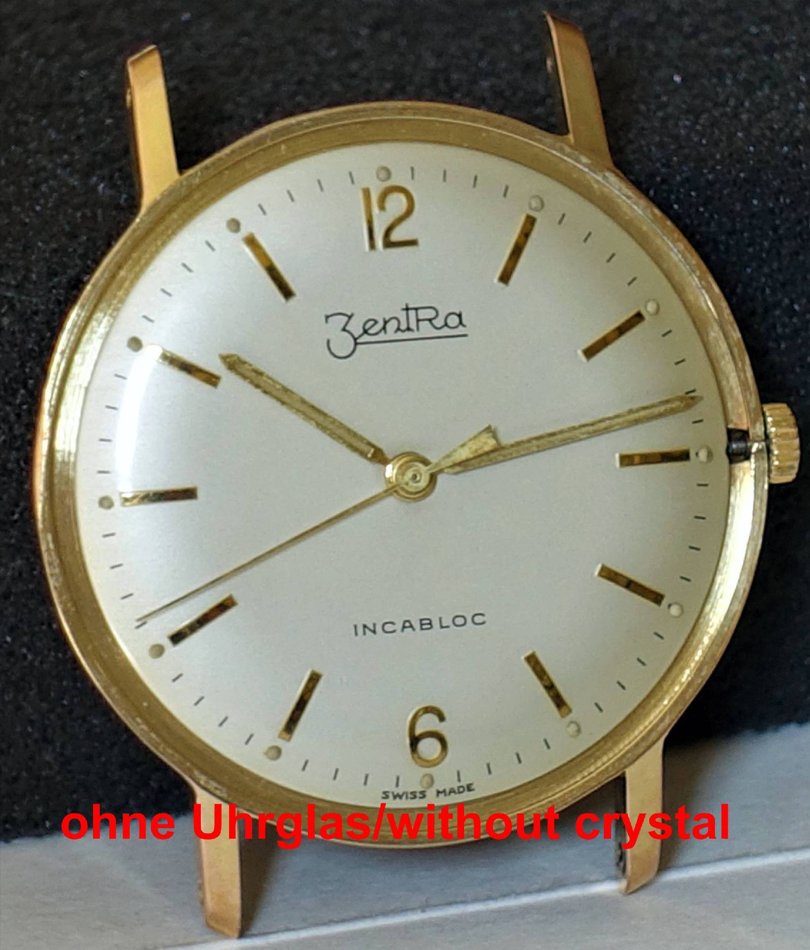 Goldfarbene Armbanduhr ohne Uhrglas mit hellem Zifferblatt und goldenen Zeigern.
