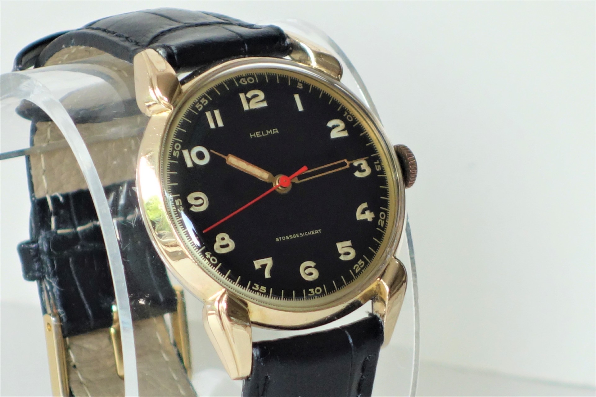 Schwarze Armbanduhr mit goldfarbenem Gehäuse und schwarzem Armband.
