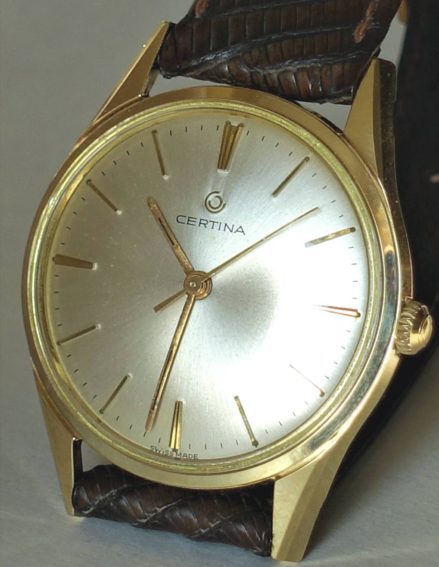 Goldfarbene Certina Armbanduhr mit hellem Zifferblatt und braunem Armband.