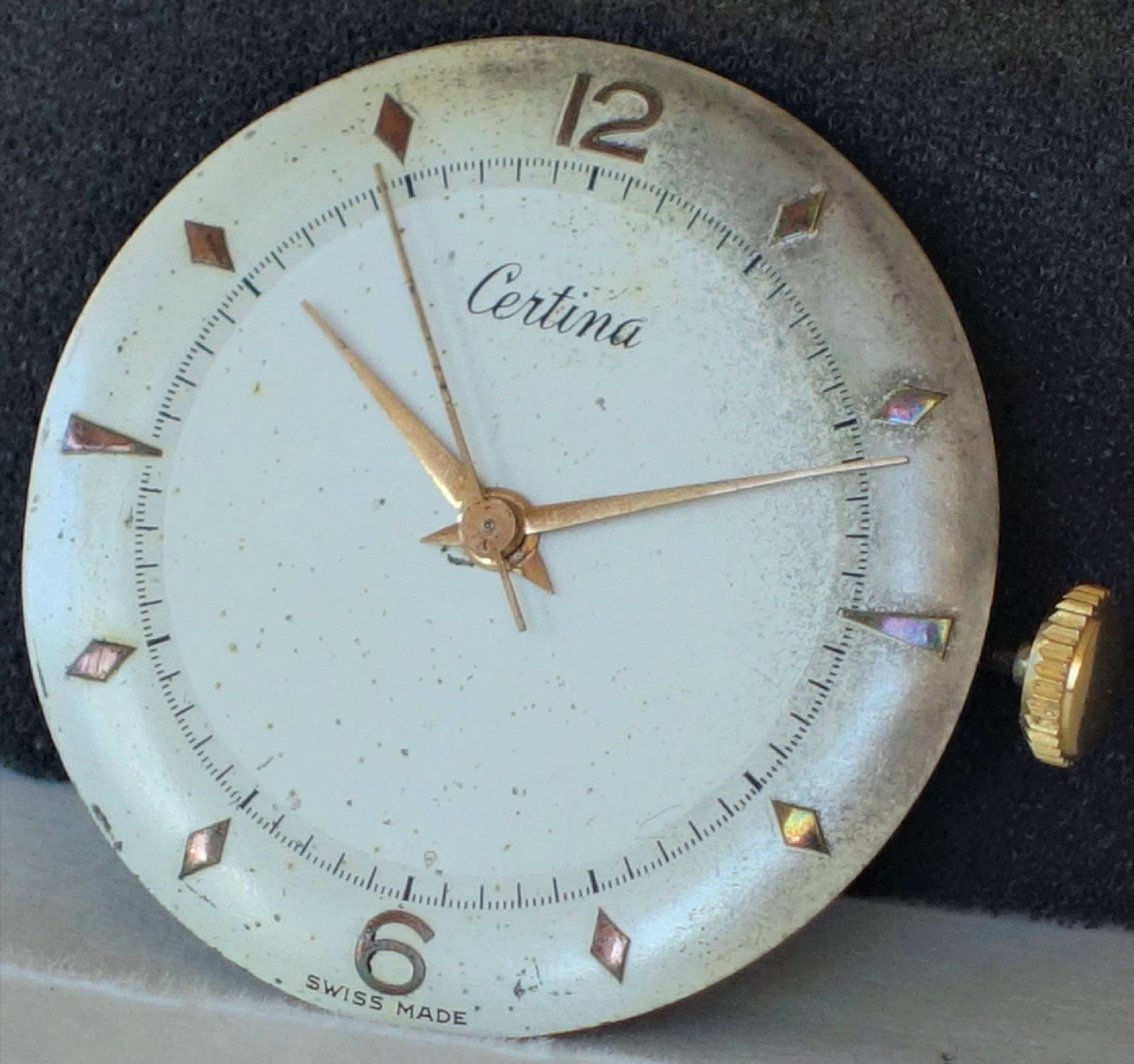 Rundes Certina Uhrwerk mit weißem Zifferblatt, goldfarbenen Zeigern und goldfarbener Krone.