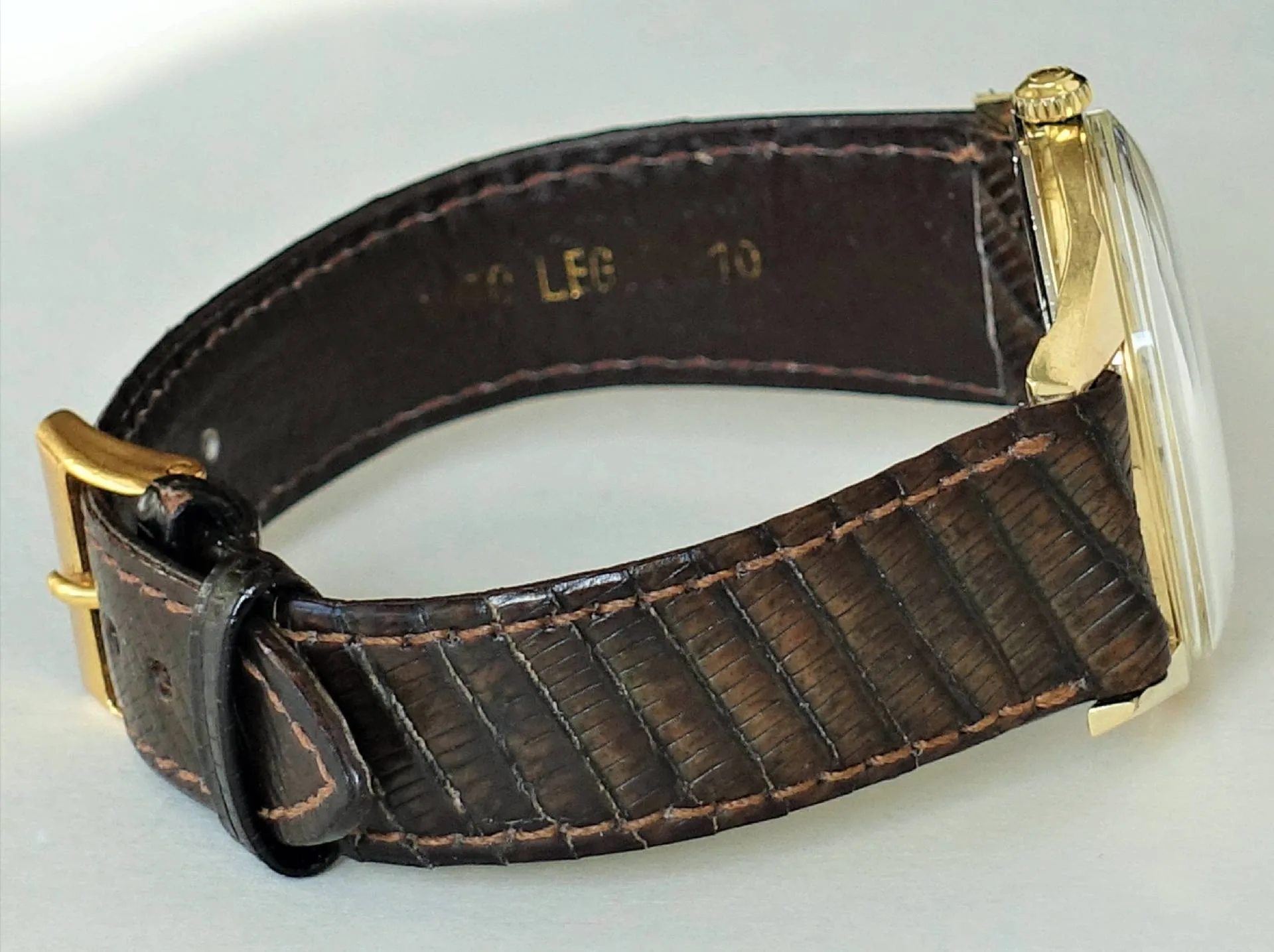Braune Armbanduhr mit goldfarbenem Gehäuse und Schließe.