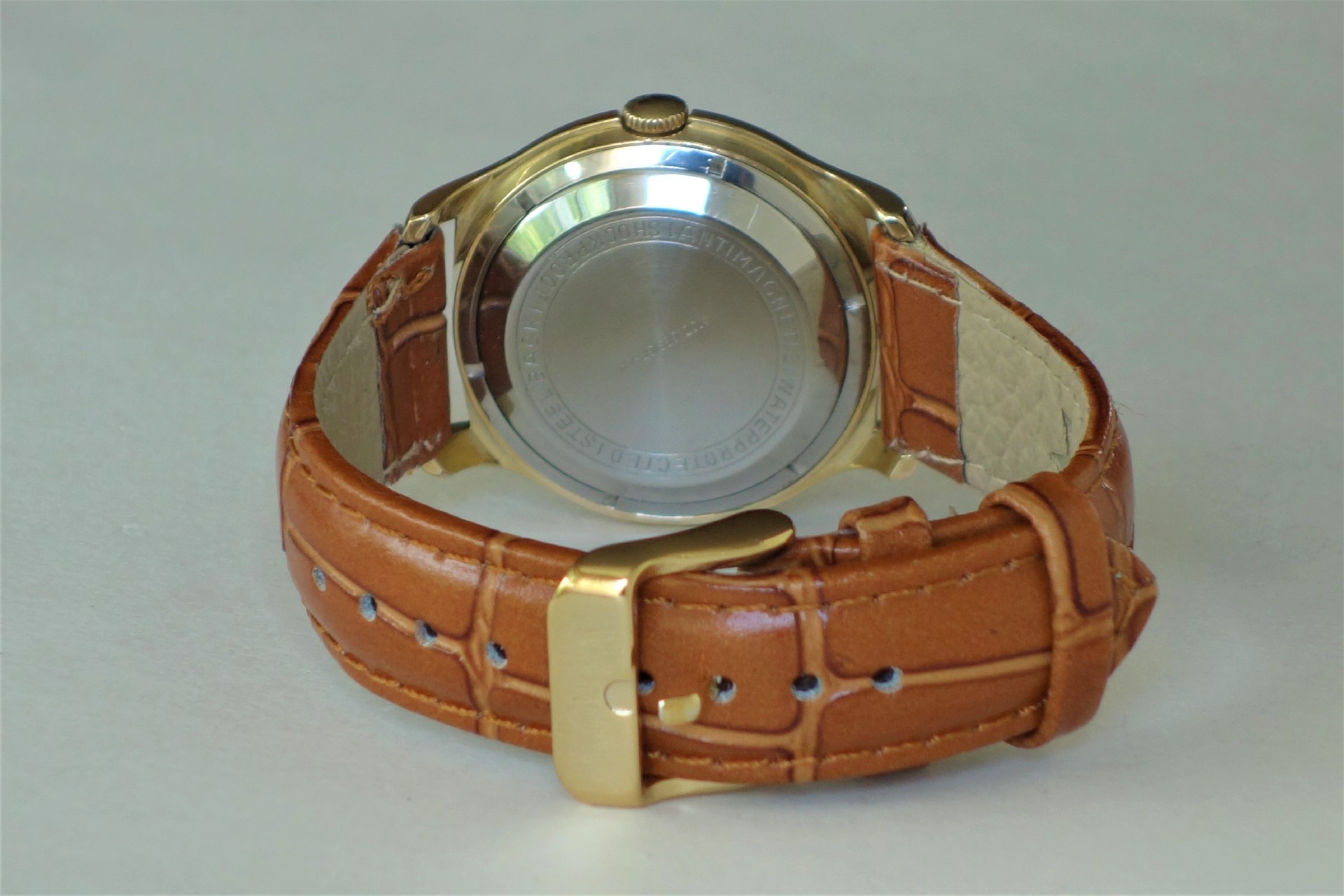 Rückseite einer Armbanduhr mit braunem Armband und silberfarbenem Gehäuse.