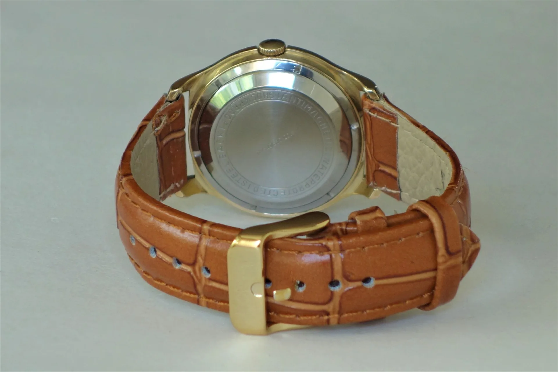 Rückseite einer Armbanduhr mit braunem Armband und silberfarbenem Gehäuse.