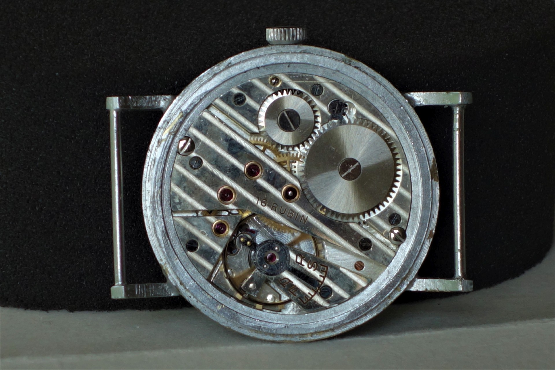 Mechanisches Uhrwerk in silberner Farbe mit sichtbaren Zahnrädern und Rubinen.