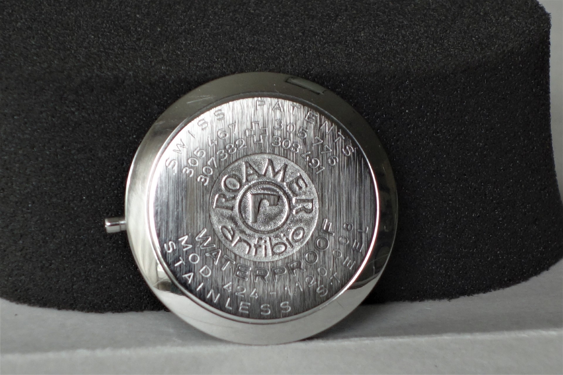 Runder silberfarbener Gehäuseboden mit eingraviertem Roamer-Logo und Schriftzug.