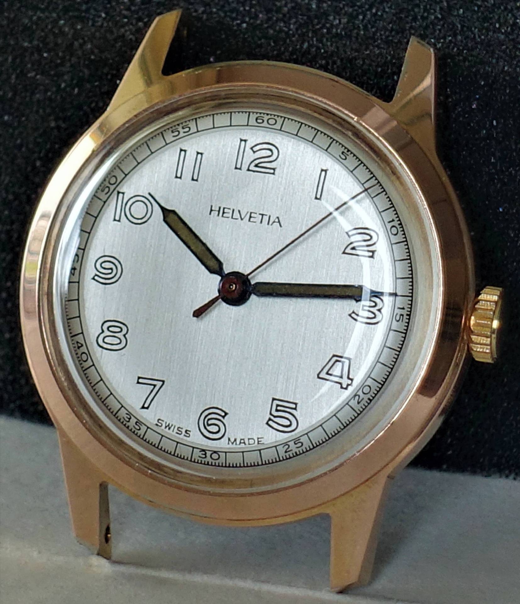 Goldfarbene Armbanduhr mit silberfarbenem Zifferblatt und schwarzen Zahlen.