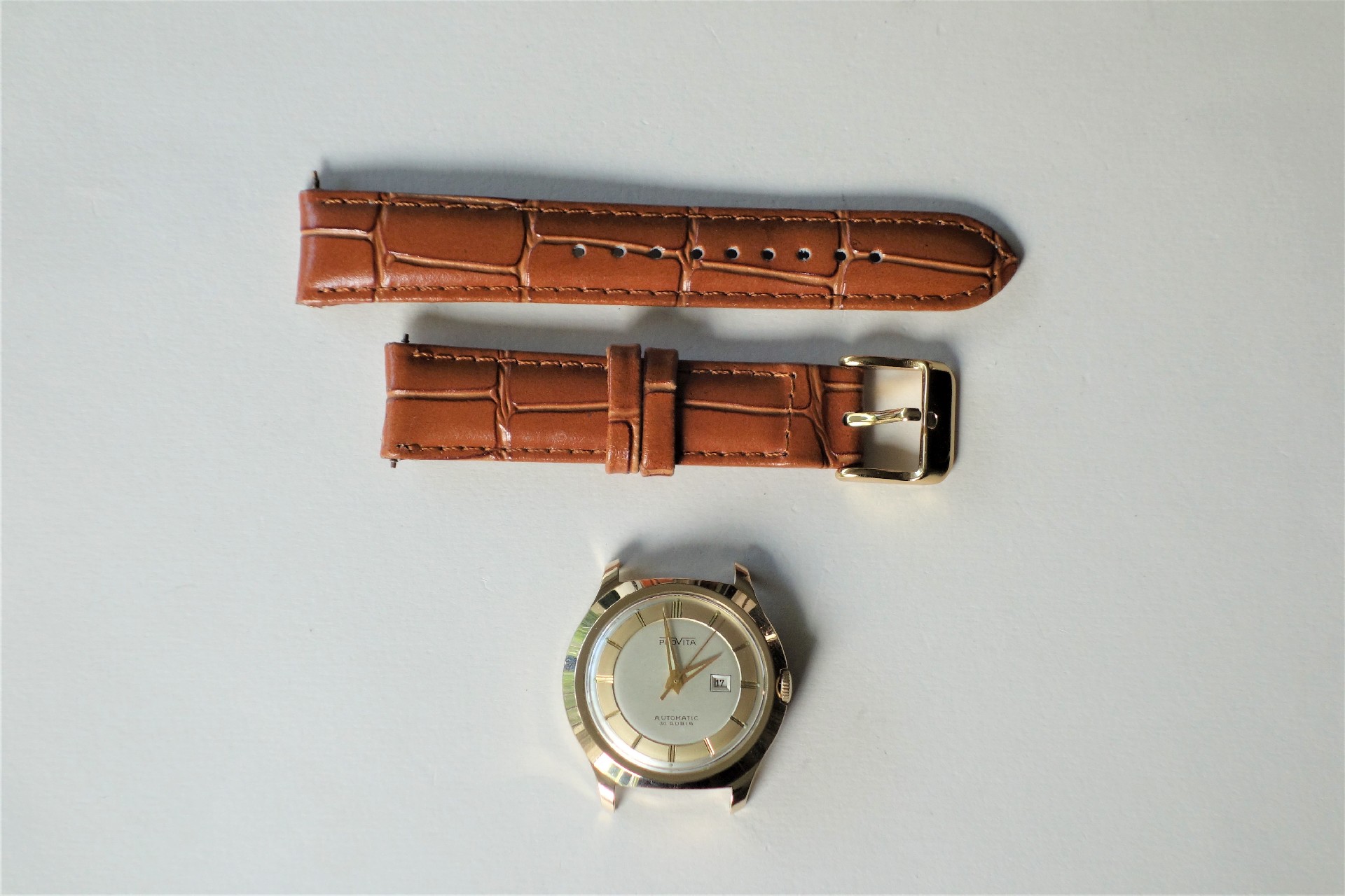 Silberfarbenes Uhrgehäuse mit hellem Zifferblatt und braunes Armband in Kroko-Optik.