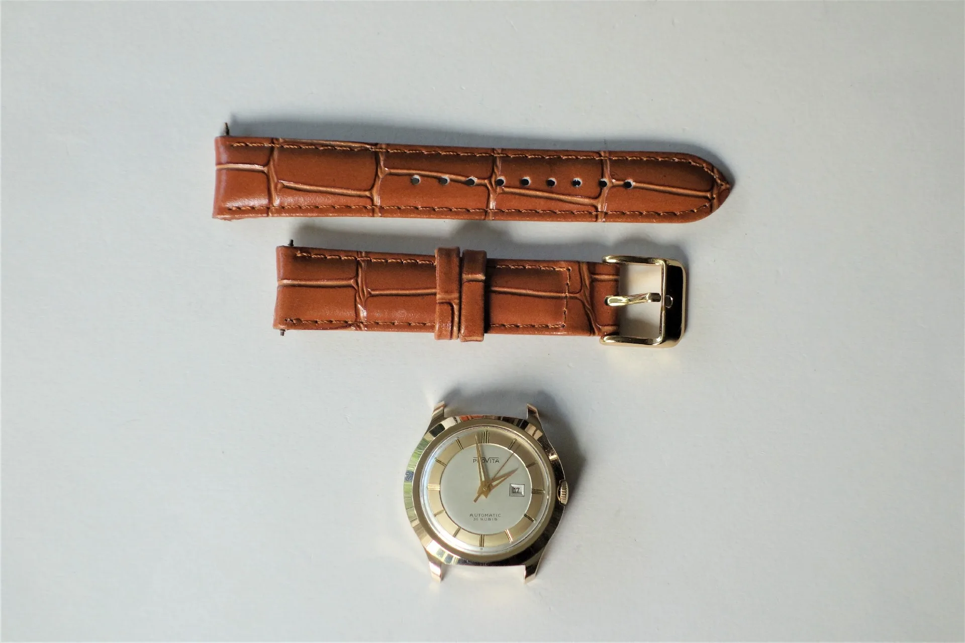 Silberfarbenes Uhrgehäuse mit hellem Zifferblatt und braunes Armband in Kroko-Optik.
