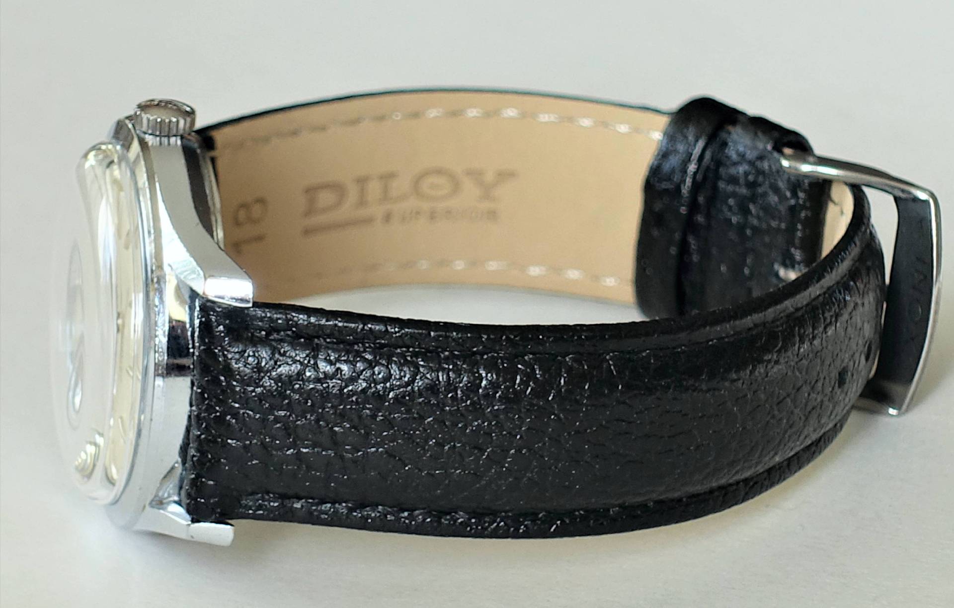 Schwarzes Armband für Uhren mit sichtbarer Schließe und Prägung auf der Innenseite.