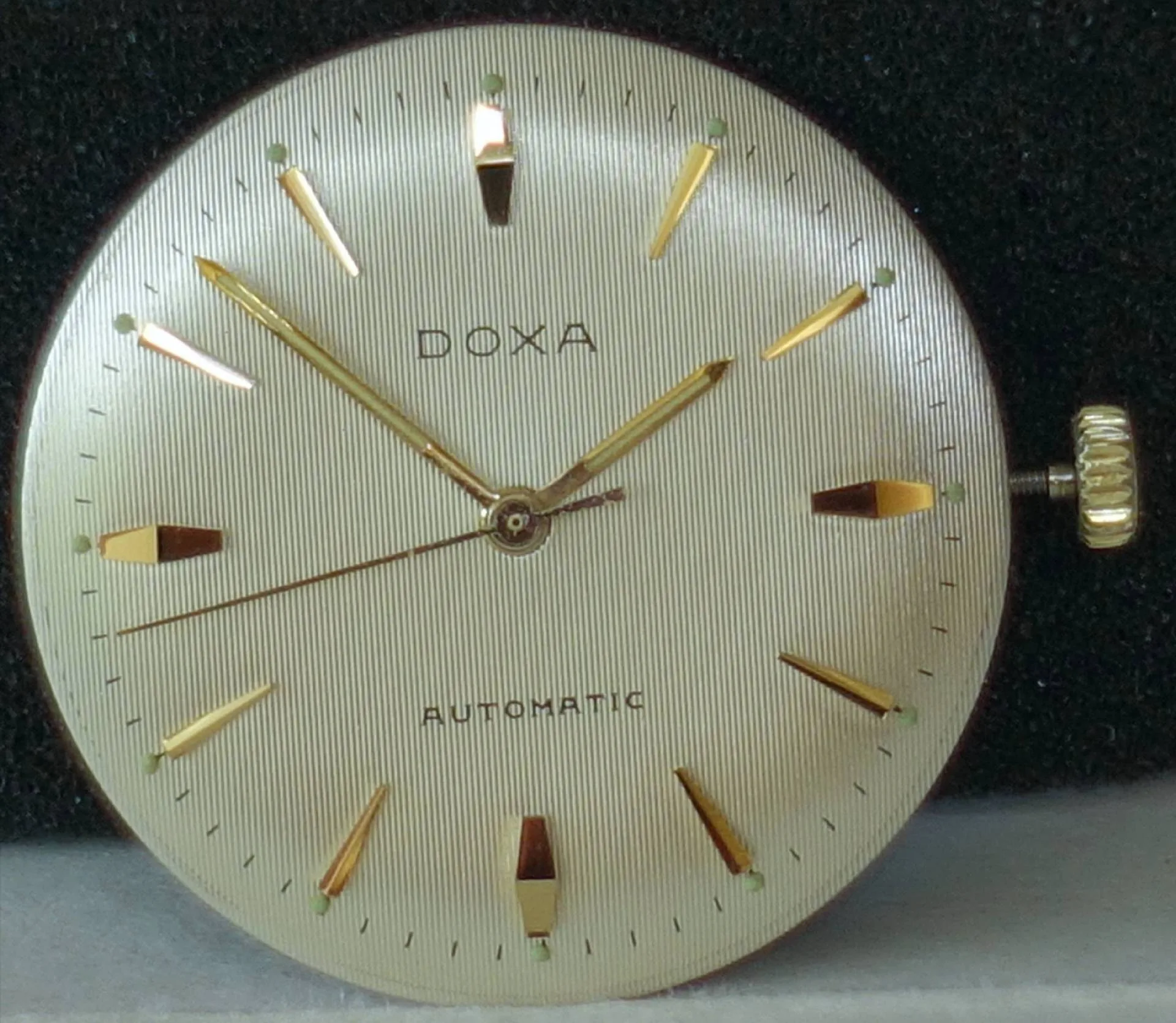 Doxa Uhrwerk mit Zifferblatt Silberfarbenes Doxa Uhrwerk mit Zifferblatt, goldfarbenen Indizes und Zeigern sowie seitlicher Krone.