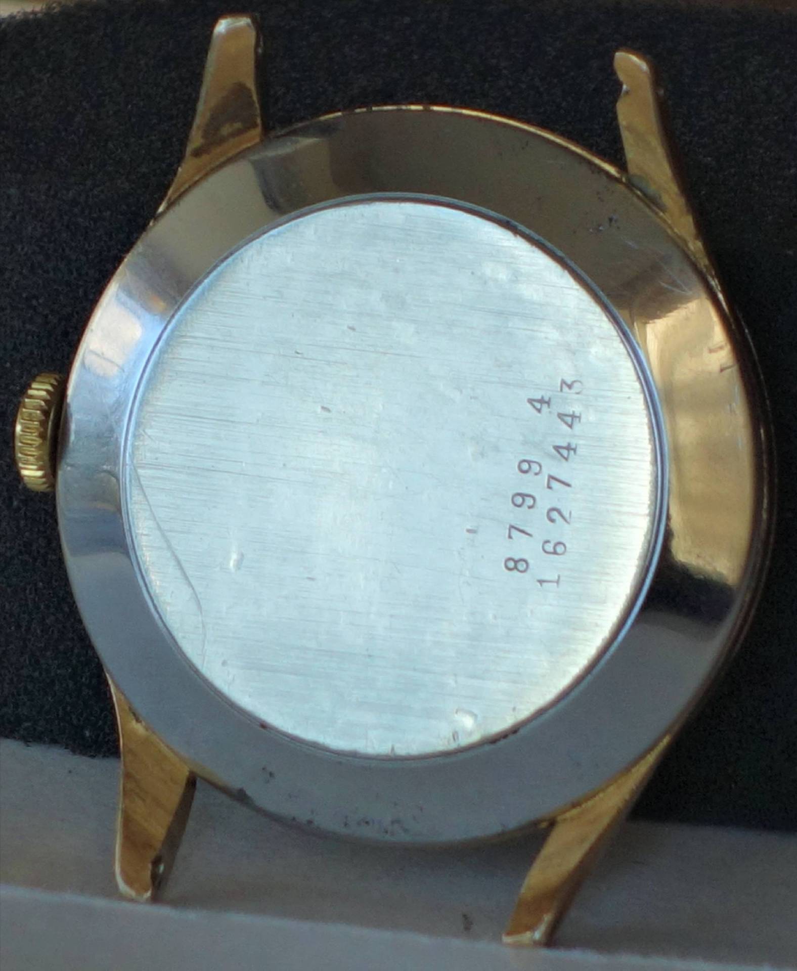 Zweifarbiges Uhrengehäuse mit silberfarbener Rückseite und goldfarbenen Hörnern, sichtbare Gravur auf dem Boden.