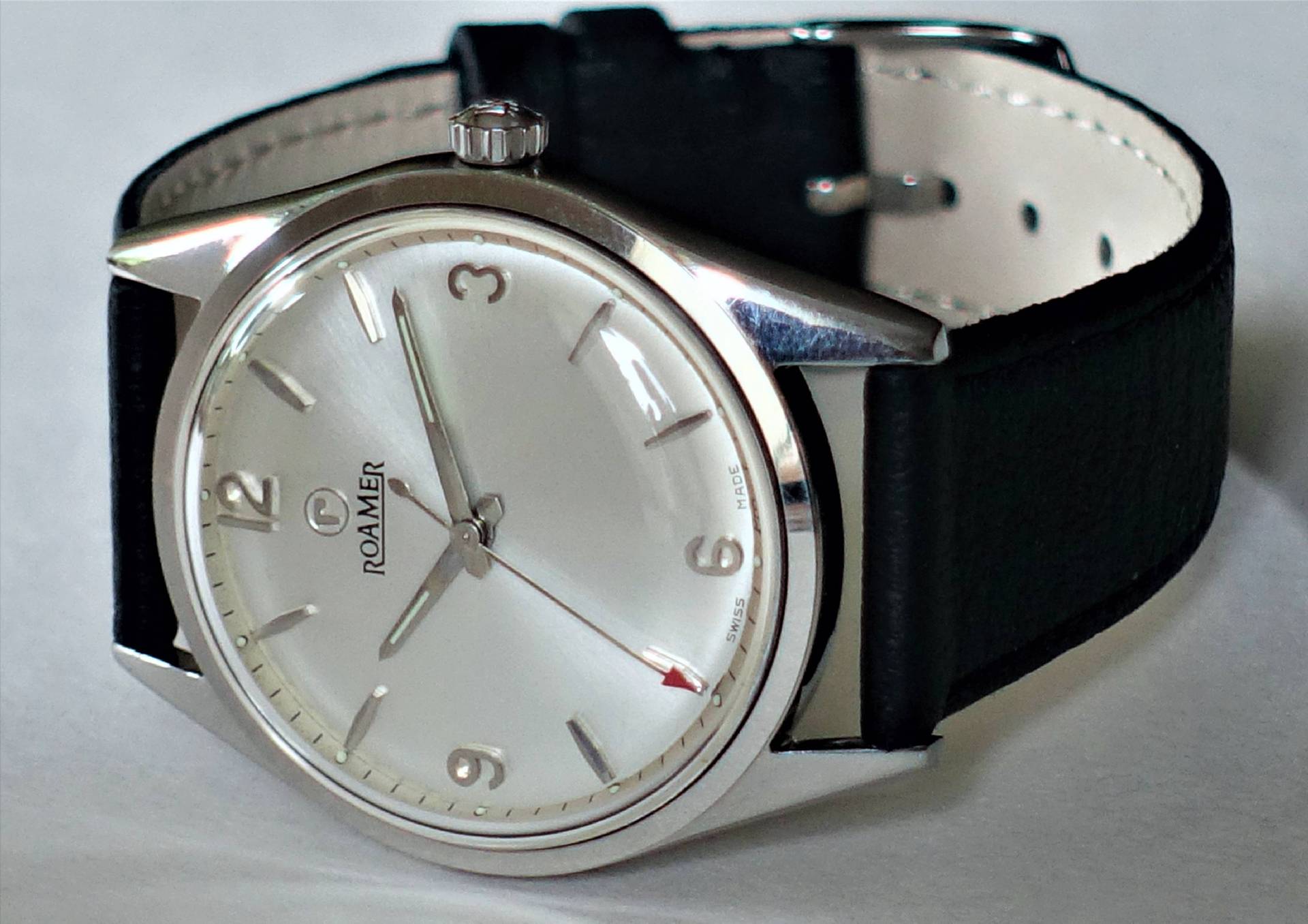 Silberfarbene Armbanduhr mit hellem Zifferblatt und schwarzem Armband.