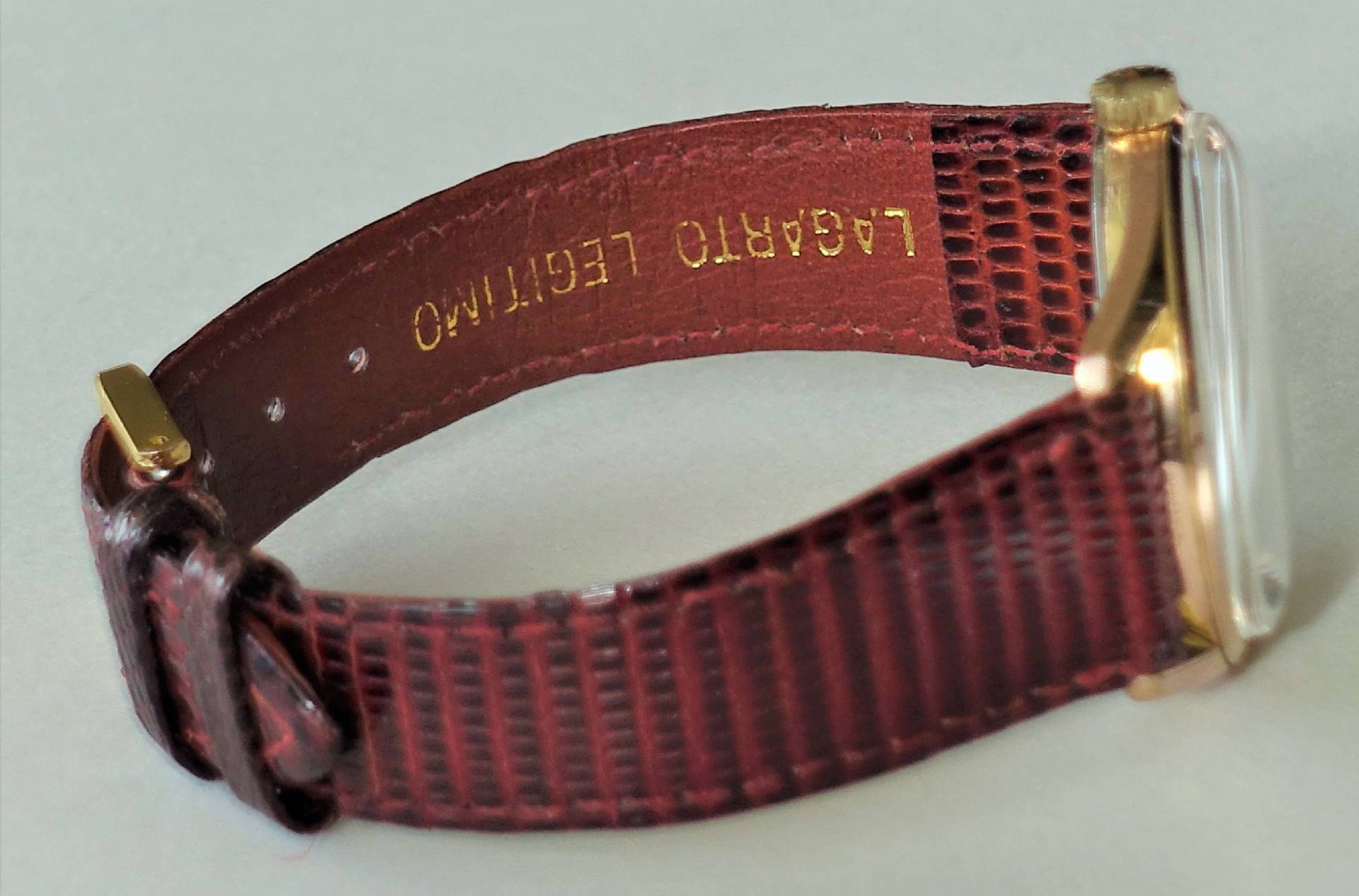 Braune Armbanduhr mit goldfarbenem Gehäuse und strukturiertem Lederarmband.