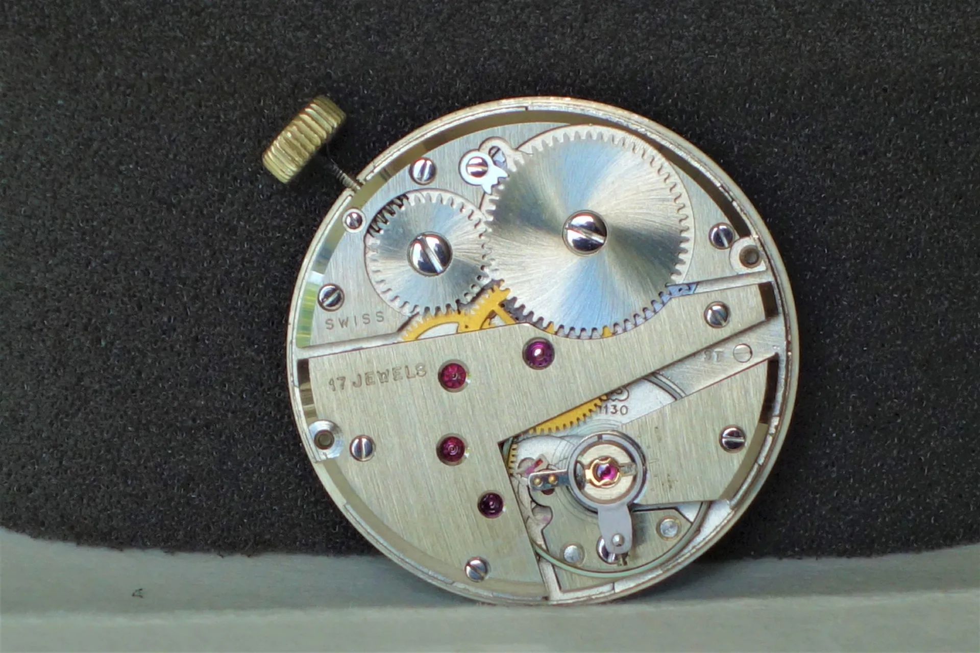 Mechanisches Uhrwerk 17 Steine Mechanisches Uhrwerk aus Metall mit sichtbaren Zahnrädern und 17 roten Lagersteinen.