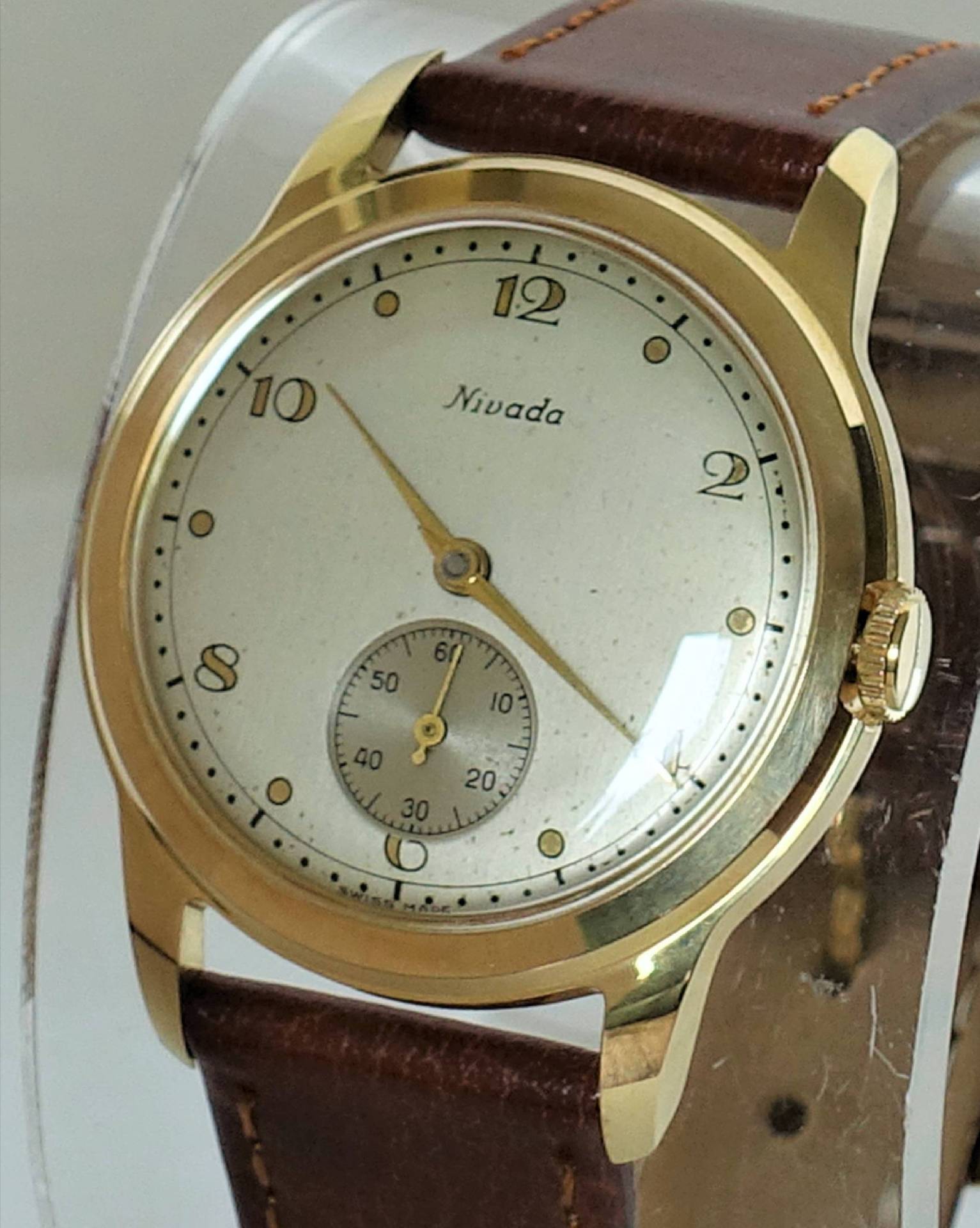 Goldfarbene Armbanduhr mit hellem Zifferblatt und braunem Lederarmband.