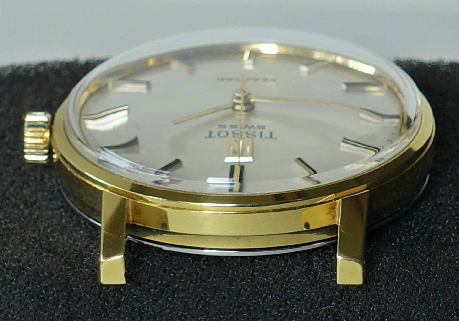 Goldfarbene Armbanduhr mit hellem Zifferblatt und Metallindizes.
