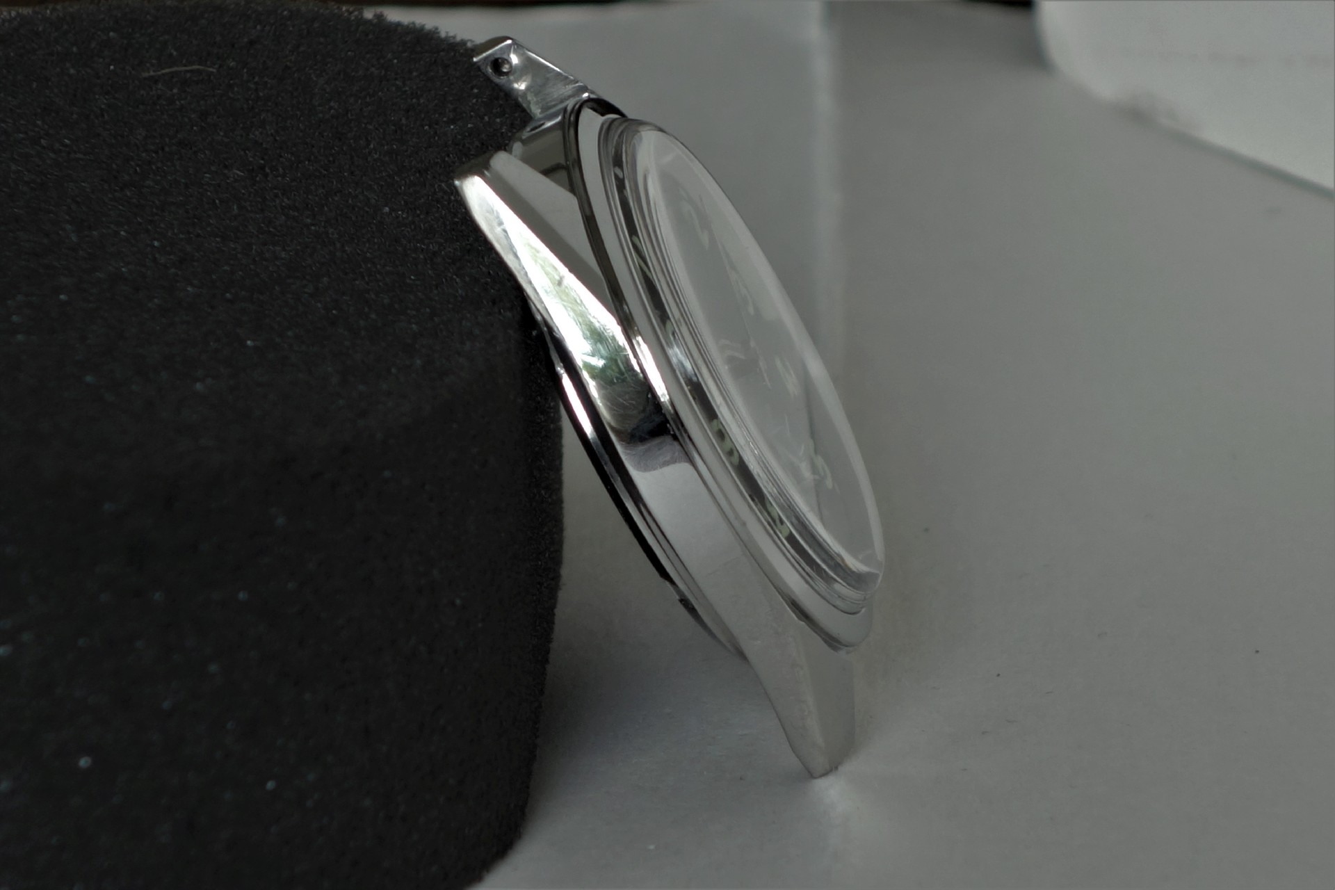 Silberfarbenes Uhrgehäuse mit montiertem Uhrglas, seitliche Ansicht.