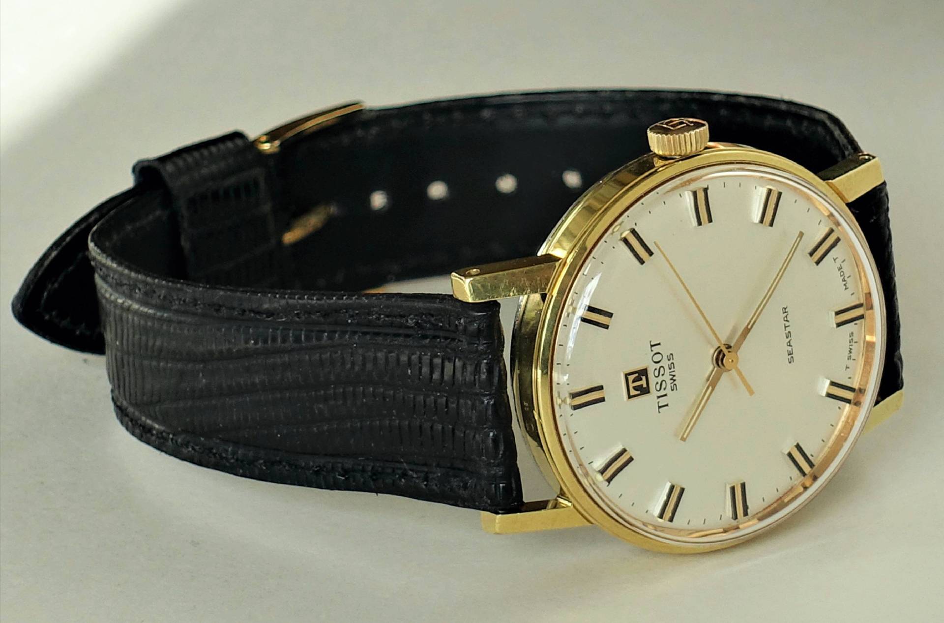 Klassische Armbanduhr mit goldfarbenem Gehäuse und schwarzem Armband.