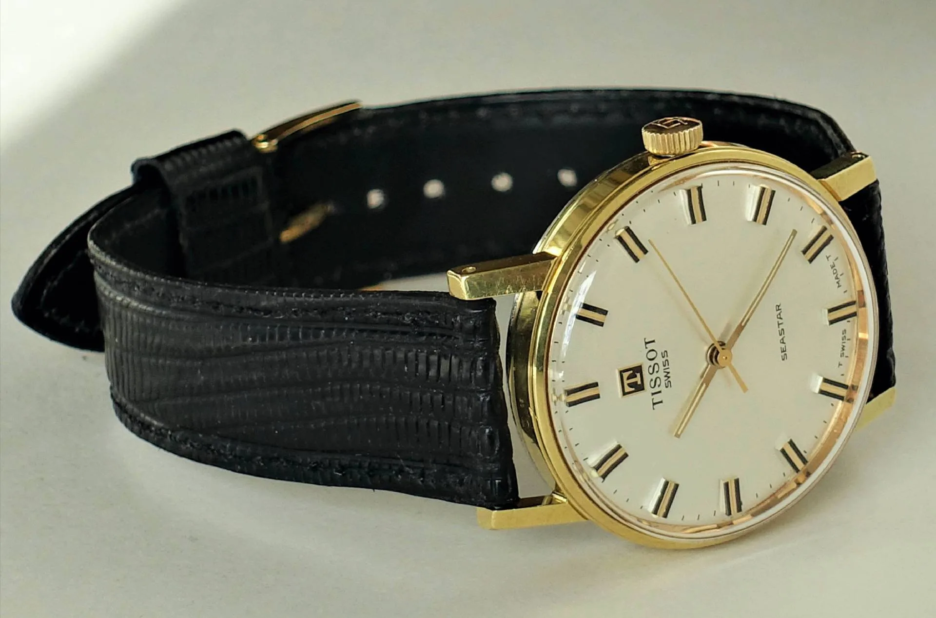 Klassische Armbanduhr mit goldfarbenem Gehäuse und schwarzem Armband.