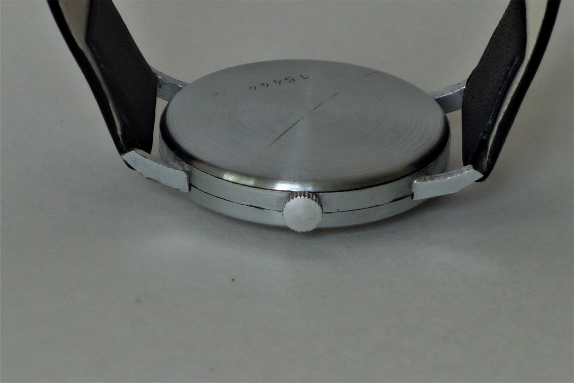 Rundes silberfarbenes Uhrengehäuse mit schwarzem Armband und seitlicher Krone.