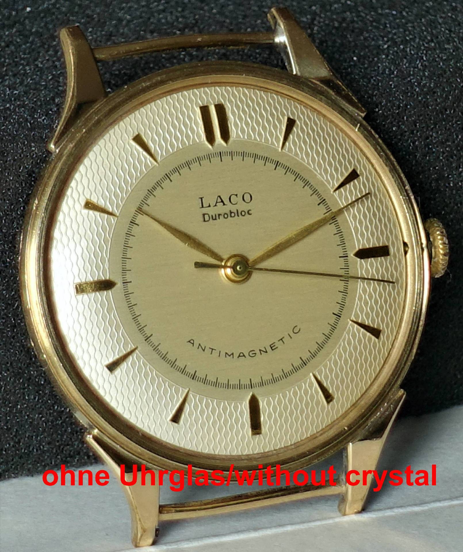 Goldfarbene analoge Armbanduhr ohne Uhrglas mit hellem Zifferblatt und goldenen Zeigern.