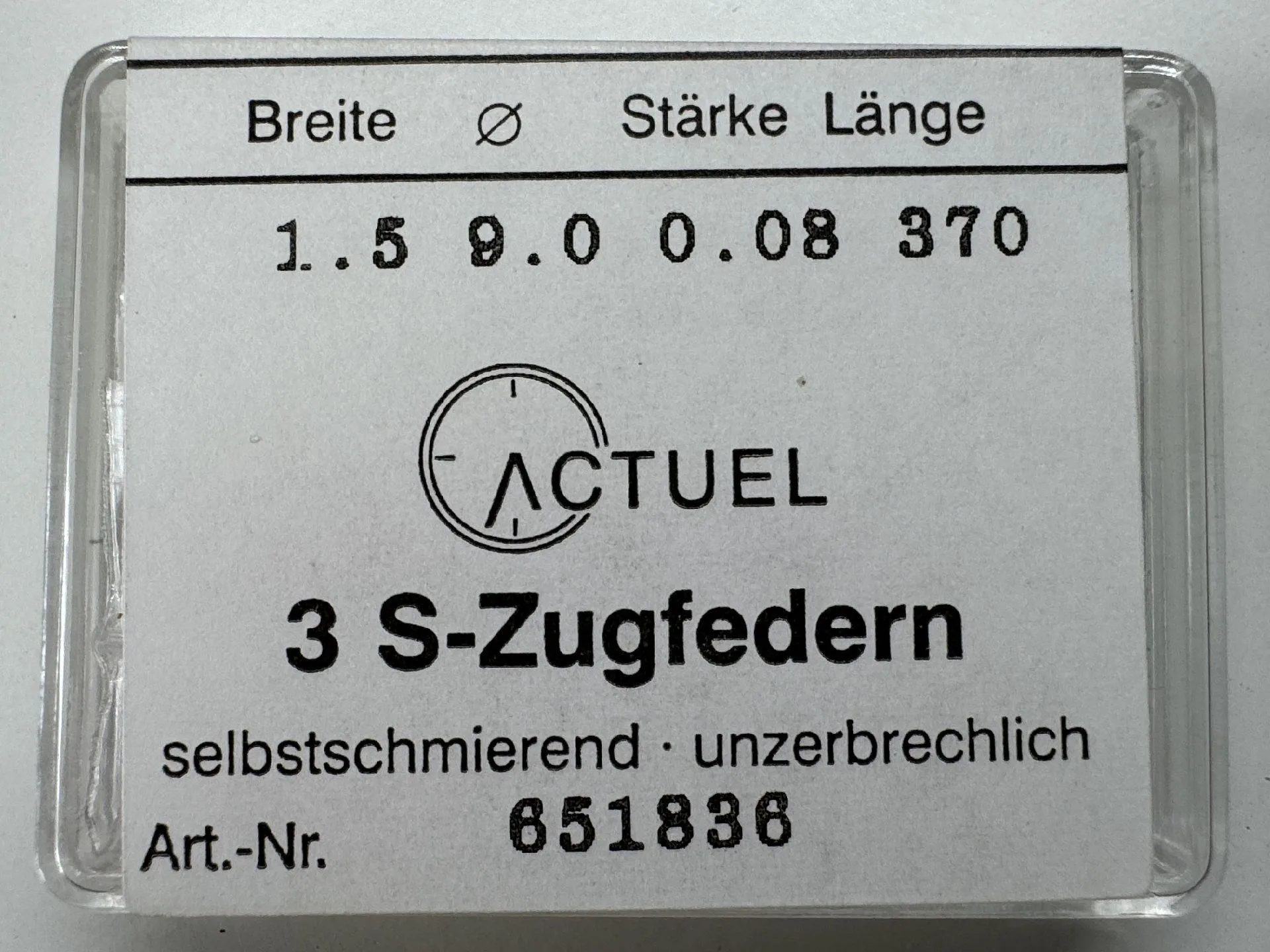 Zugfeder Set Set mit drei silberfarbenen Zugfedern für Uhren in transparenter Verpackung.