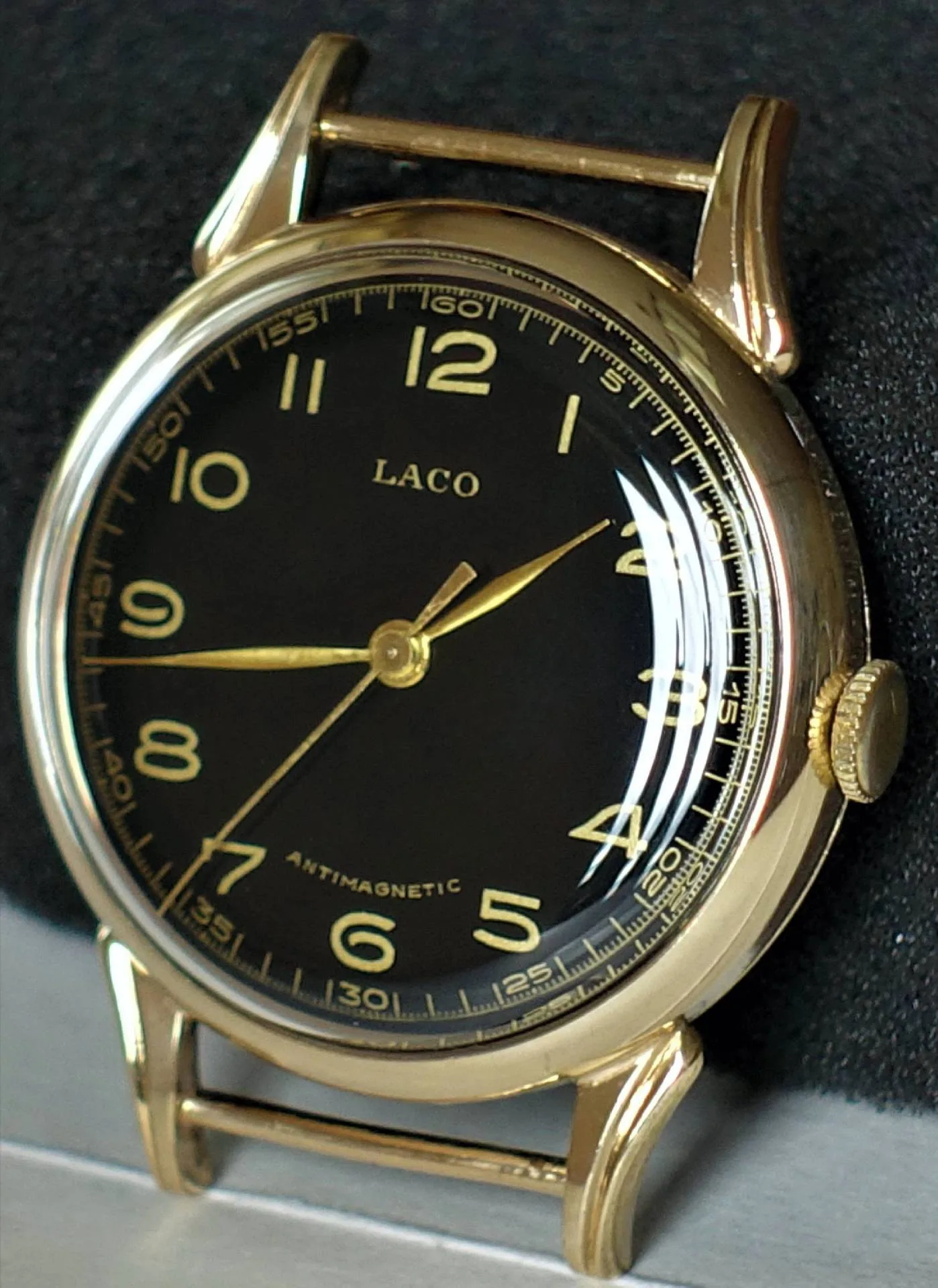 Gold Schwarz Goldfarben Schwarz Eine Armbanduhr mit goldfarbenem Gehäuse, schwarzem Zifferblatt und goldfarbenen Zeigern sowie Ziffern.
