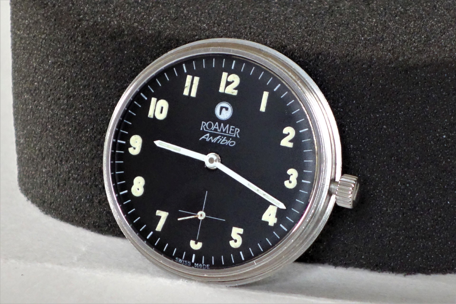 Schwarzes Uhrwerk mit weißer Krone und Leuchtziffern, Zifferblatt mit Roamer Antibio Aufschrift.