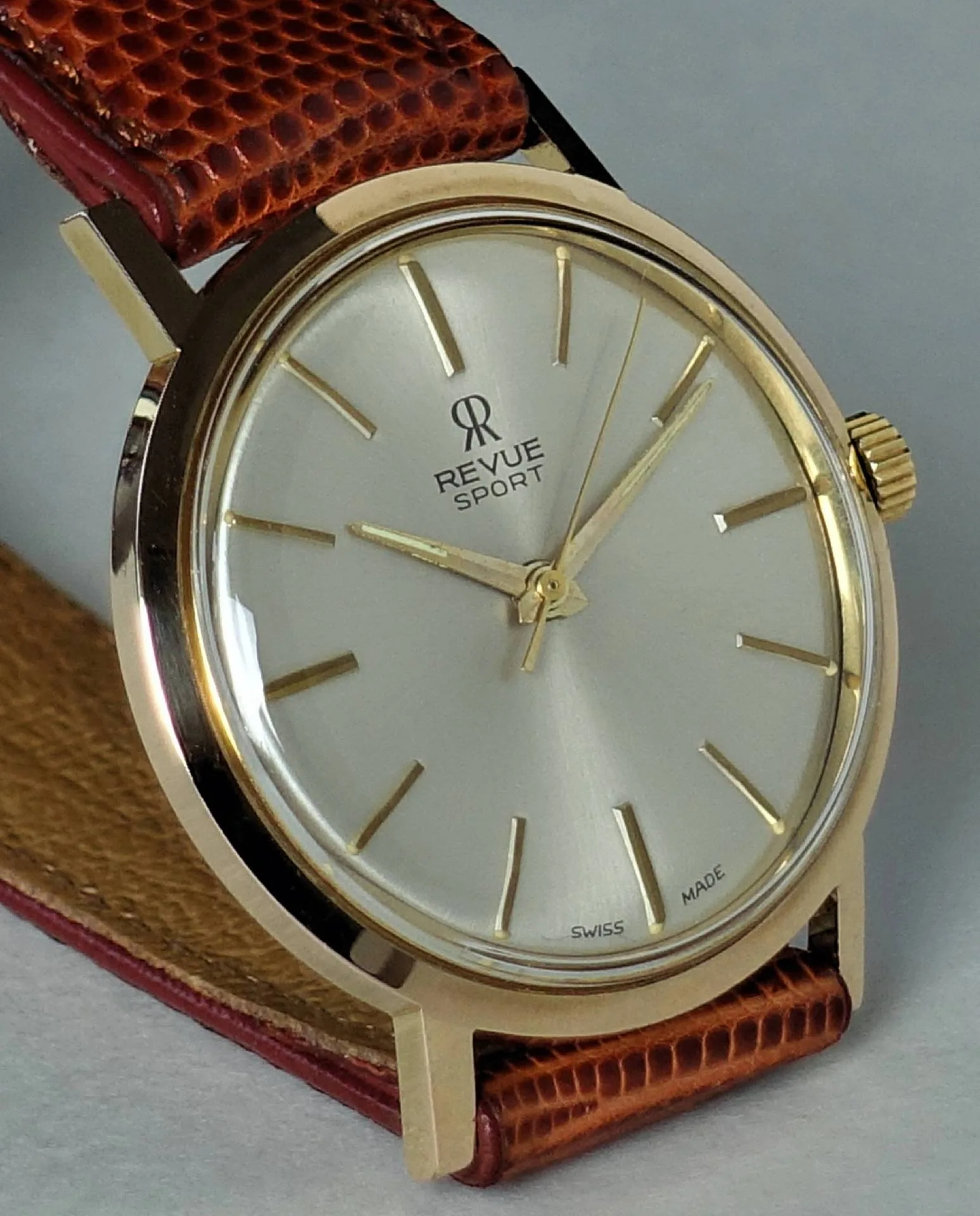 Revue Sport Armbanduhr Klassische Armbanduhr mit hellem Zifferblatt, goldfarbenem Gehäuse und braunem Armband.