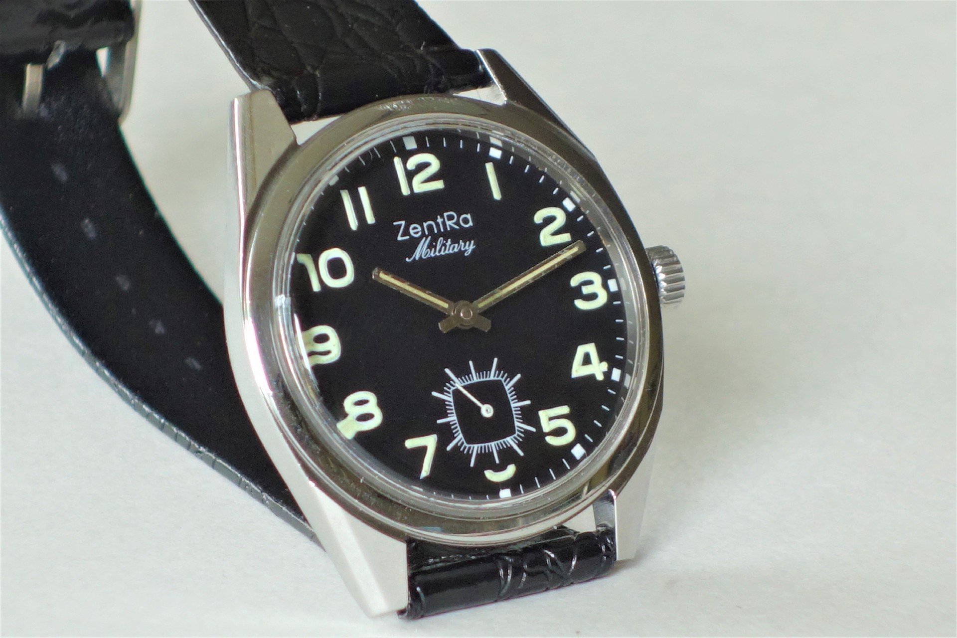 Schwarze Armbanduhr mit hellem Zifferblatt und schwarzem Armband.