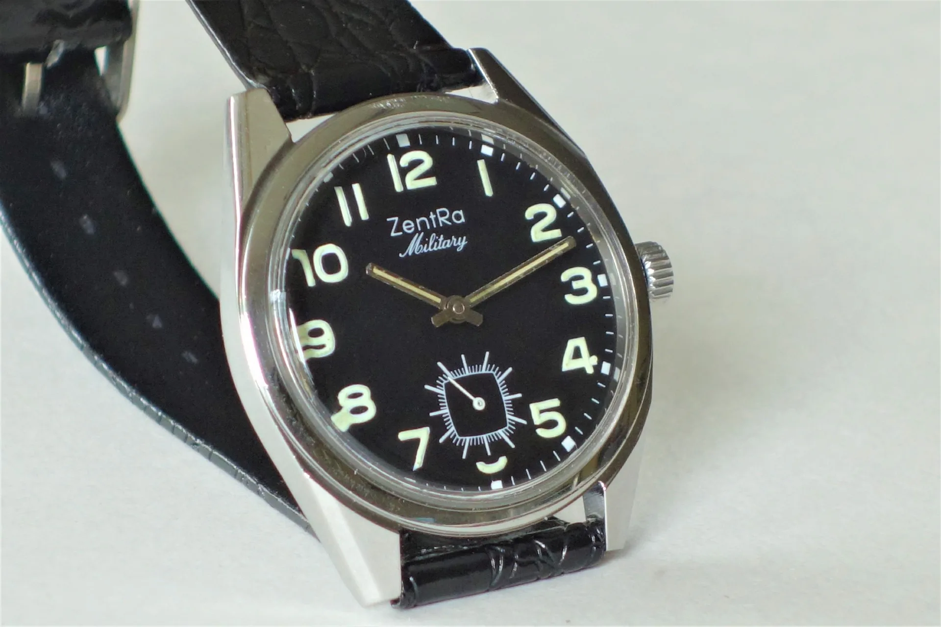 Schwarze Armbanduhr mit hellem Zifferblatt und schwarzem Armband.