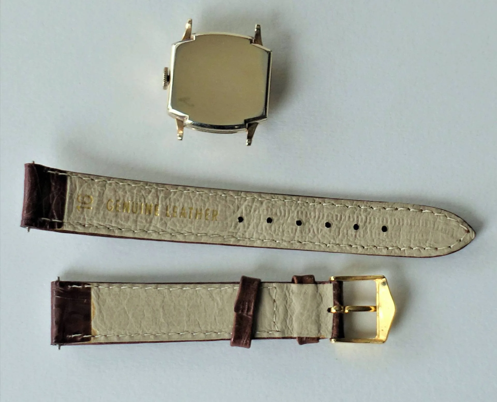 Beige-braunes Lederarmband, gelbes Gehäuse Zerlegte Armbanduhr mit beigem und braunem Lederarmband sowie einem gelbfarbenen Uhrengehäuse auf weißem Hintergrund.
