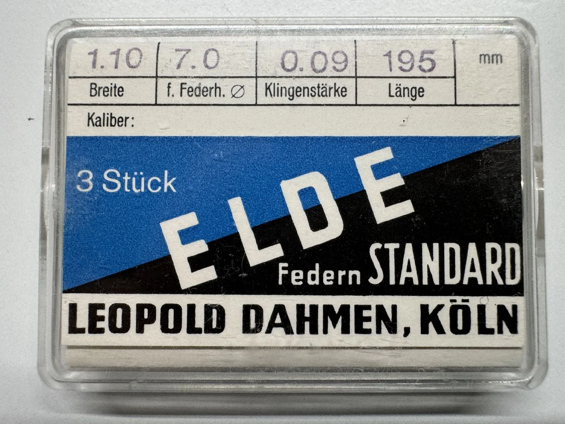 Verpackung mit drei Metall-Zugfedern für Uhren, beschriftet mit technischen Maßen.