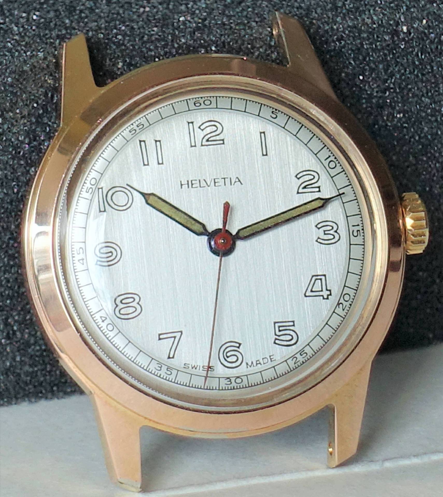 Goldfarbene Armbanduhr mit silberfarbenem Zifferblatt und schwarzen Ziffern.